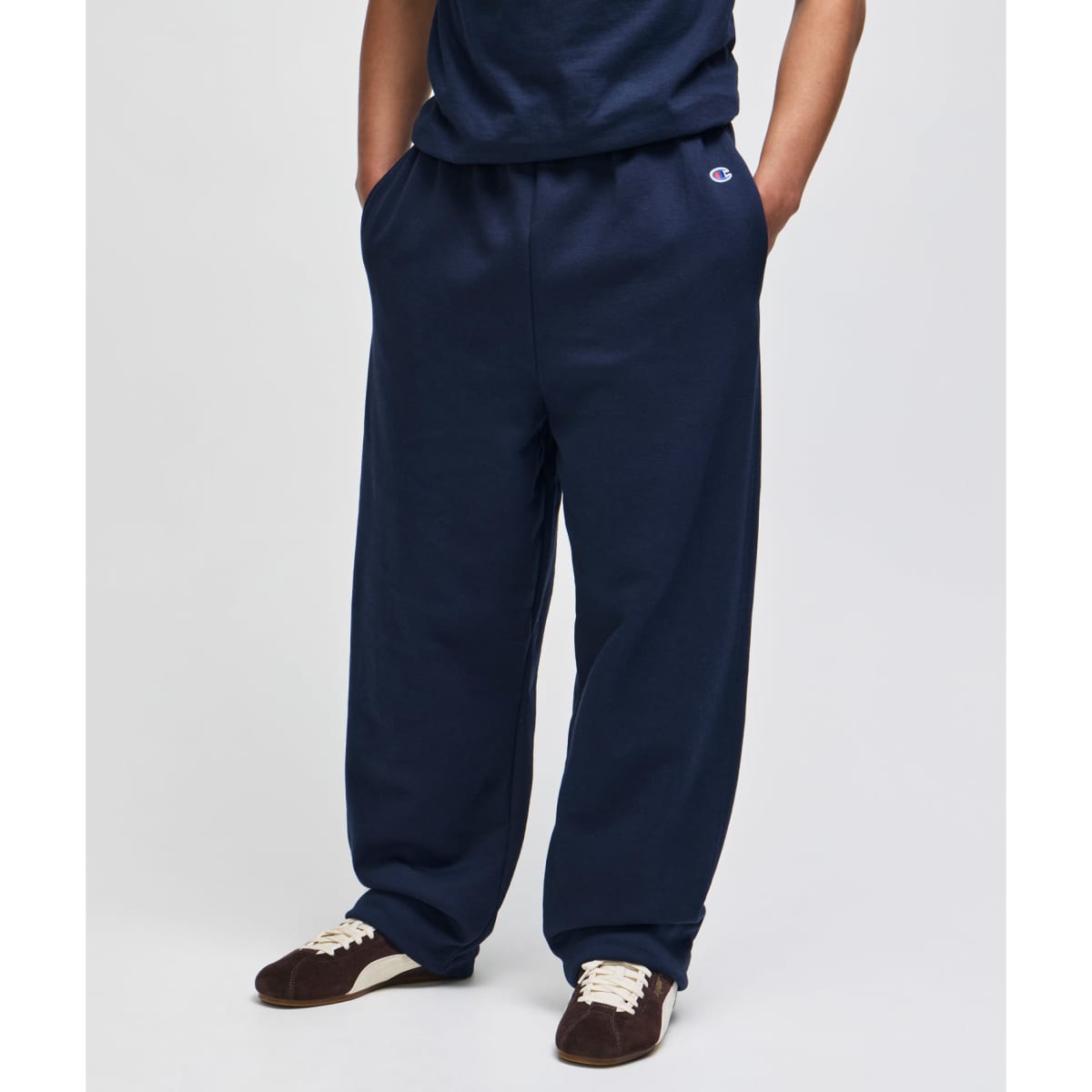 Navy fleece track pants with an open bottom and pockets, featuring a branding logo on the waistband.