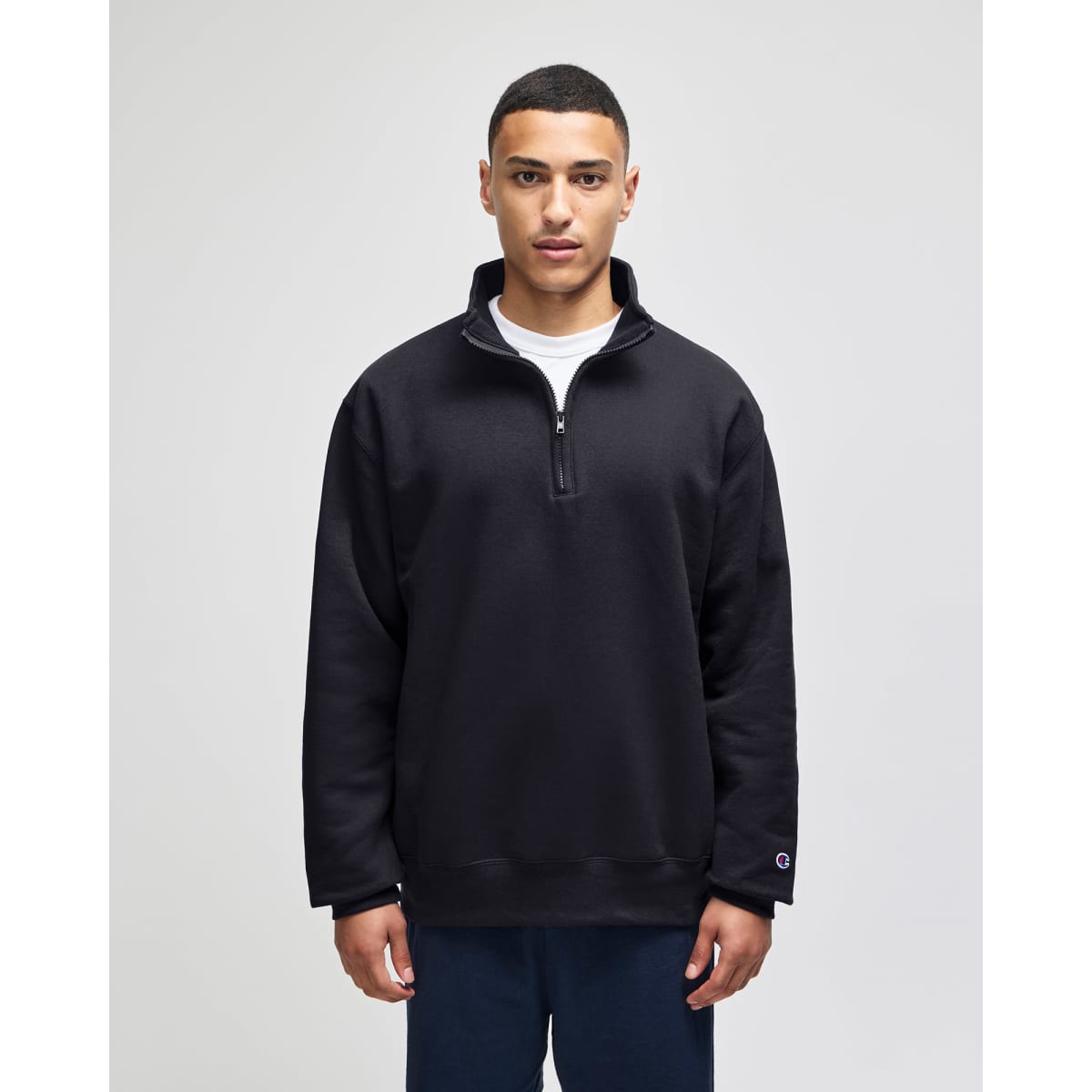 A black quarter-zip pullover with a relaxed fit, featuring a collar and a logo on the sleeve.