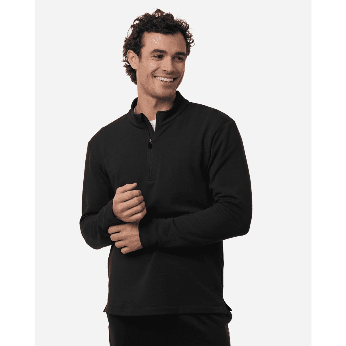 A man wearing a black stretch fleece 1/4 zip top with a smile, featuring a logo on the chest.