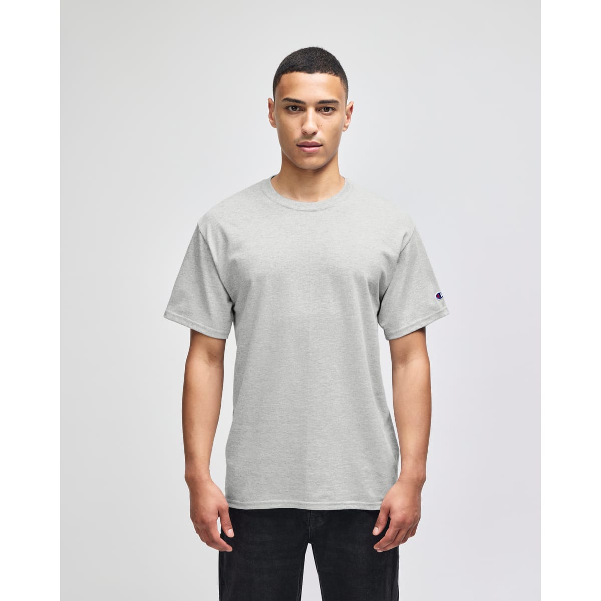 A grey short-sleeve t-shirt featuring a logo on the sleeve, displayed on a model.
