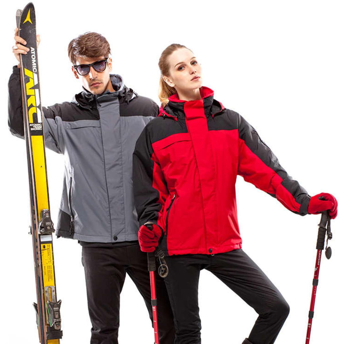 A grey and red rain jacket worn by a man and woman, with ski equipment in hand. The jackets feature branding.