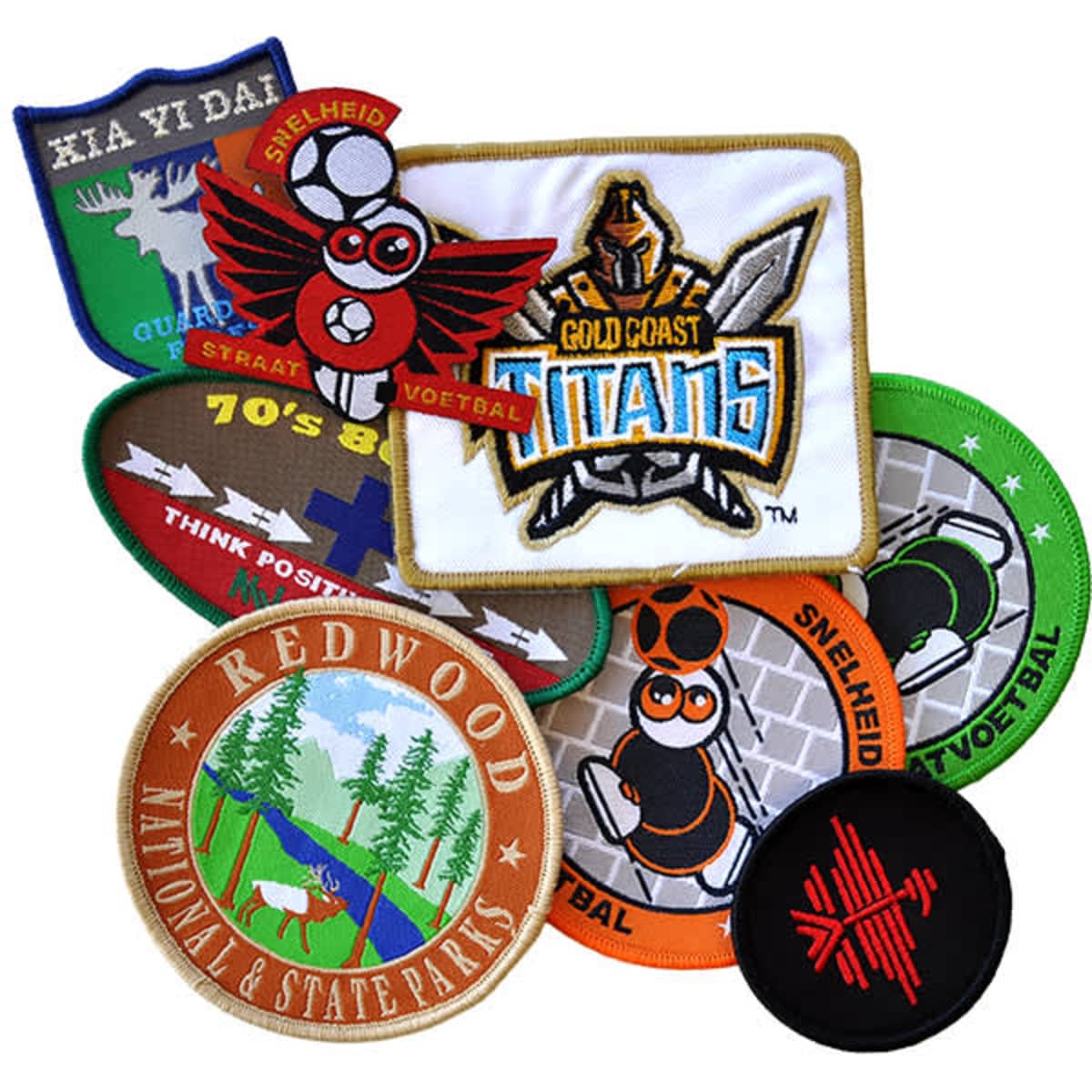 A collection of woven patches in various colours, featuring different designs and a logo, arranged on a white background.