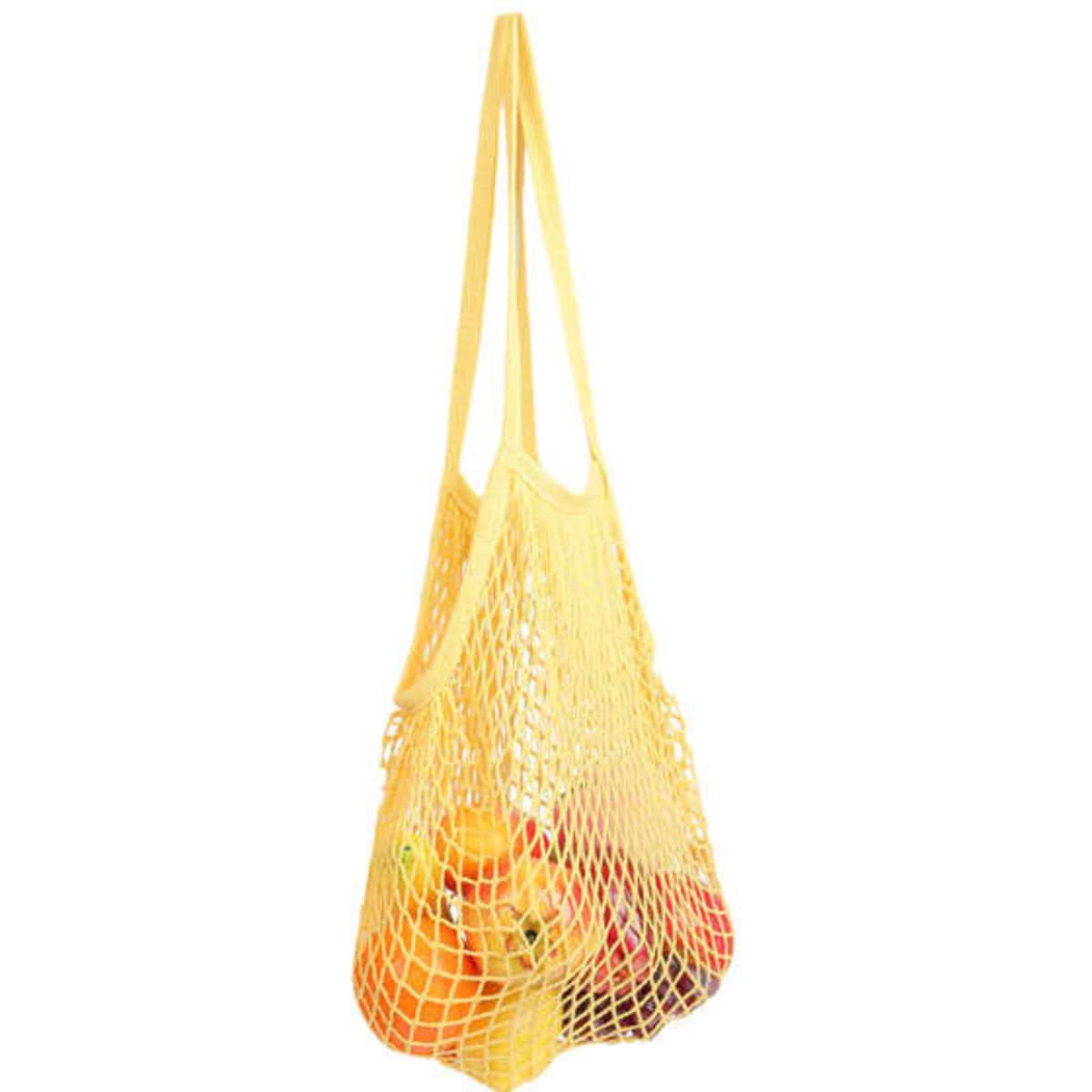 A yellow reusable cotton mesh shopping bag filled with various fruits. It features a simple design with long straps.