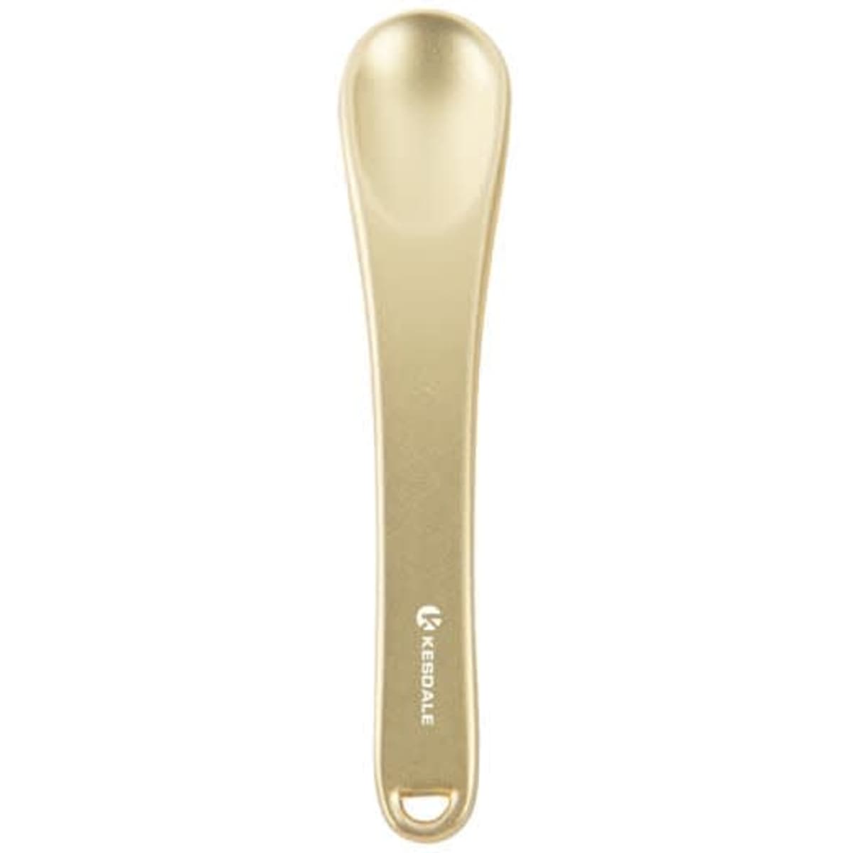 A gold metal cosmetic spatula with a smooth, rounded end and a branding logo on the handle.