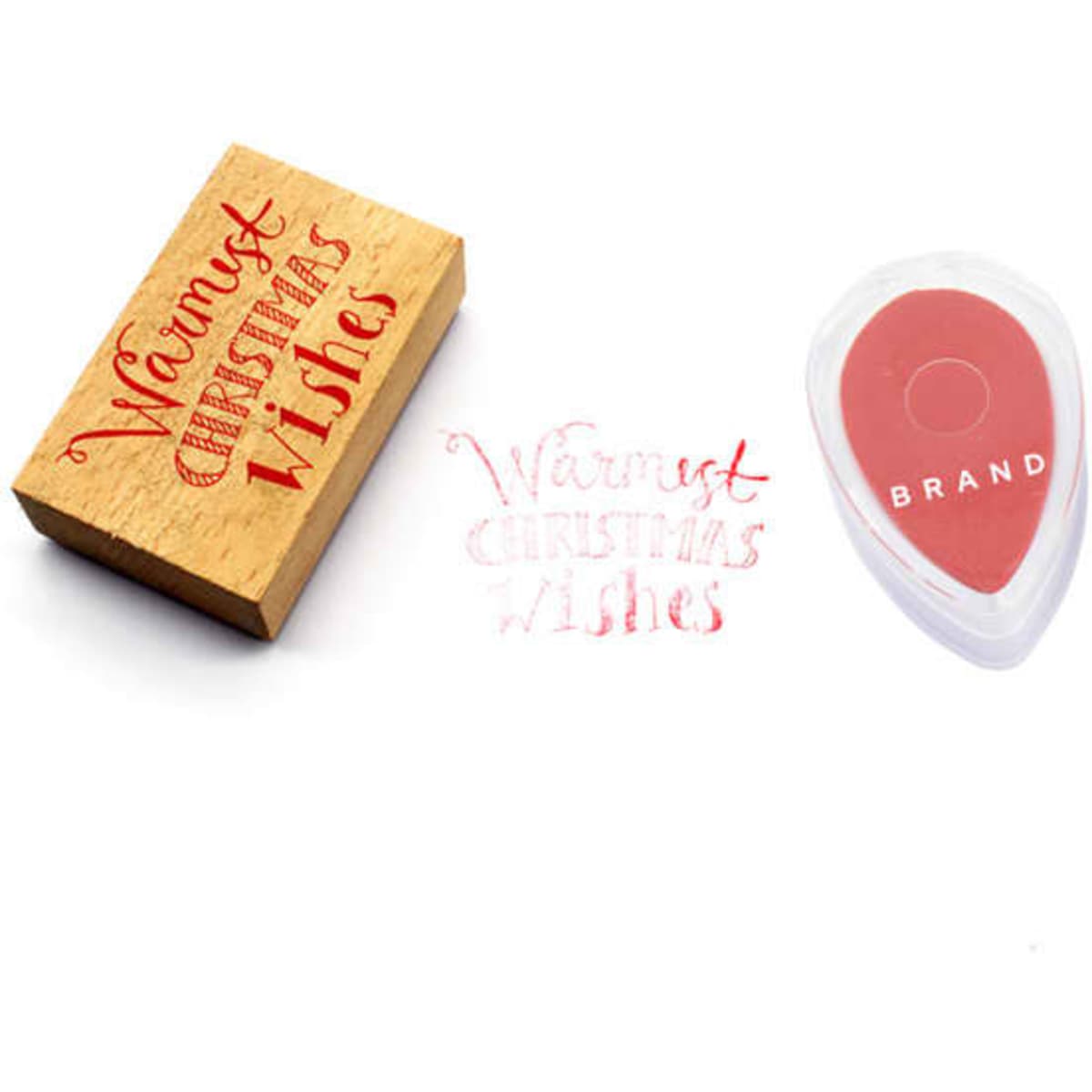 A mini inkpad in a water droplet shape, featuring red ink, alongside a wooden stamp with "Warmest Christmas Wishes."