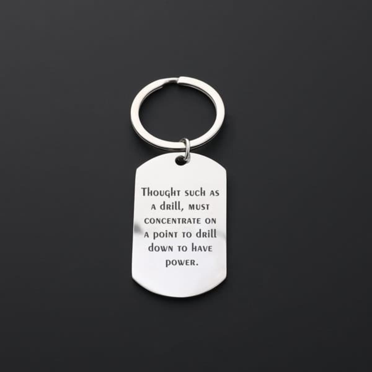 A stainless steel keychain with a circular ring and a rectangular tag featuring an engraved message.