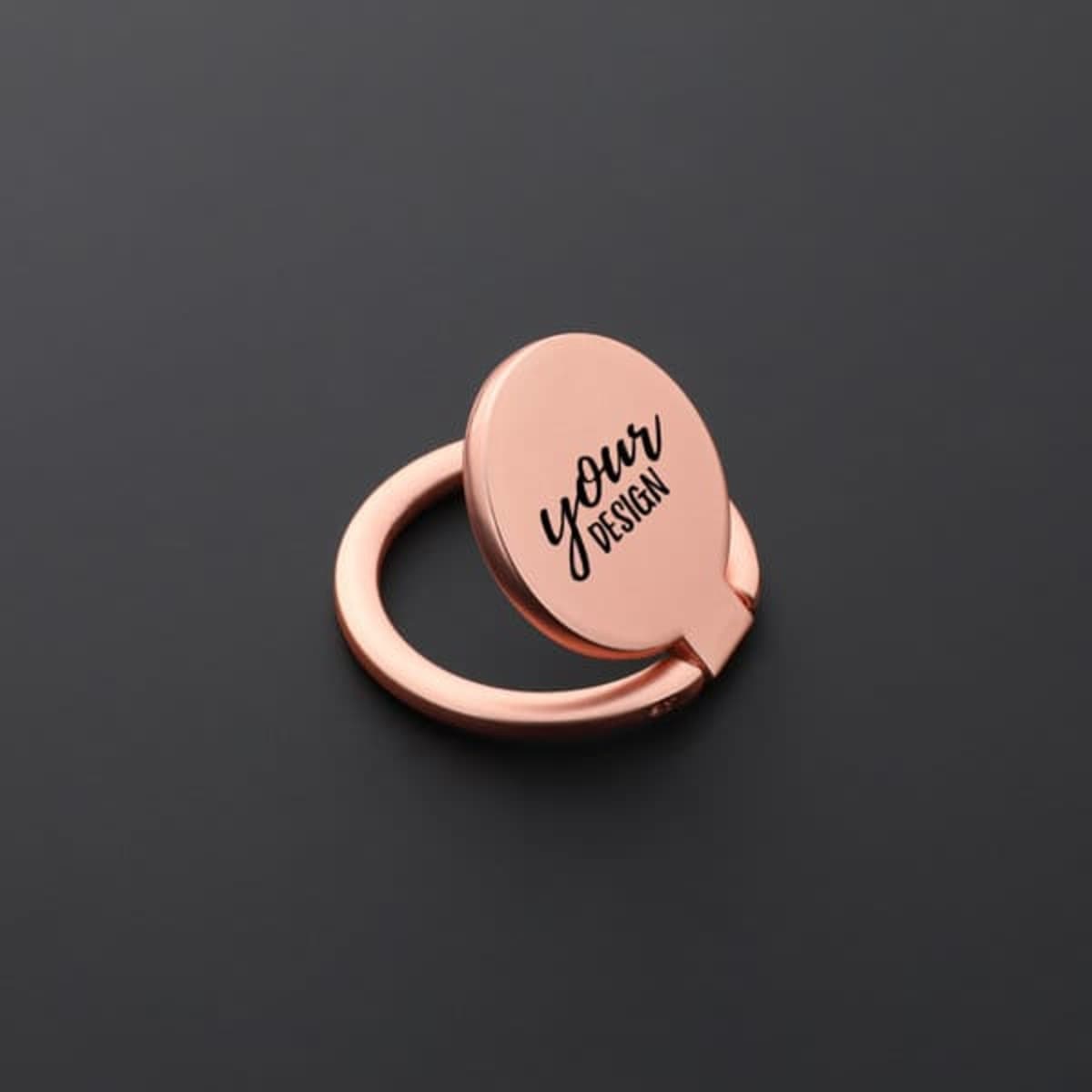 A rose gold metal finger ring holder for mobile phones featuring a customisable design area and a circular shape.