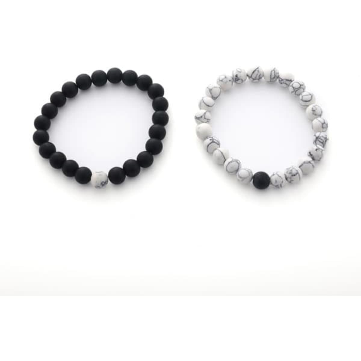 A pair of bracelets featuring black lava stones and white marbled stones, each with a smooth design and an understated style.