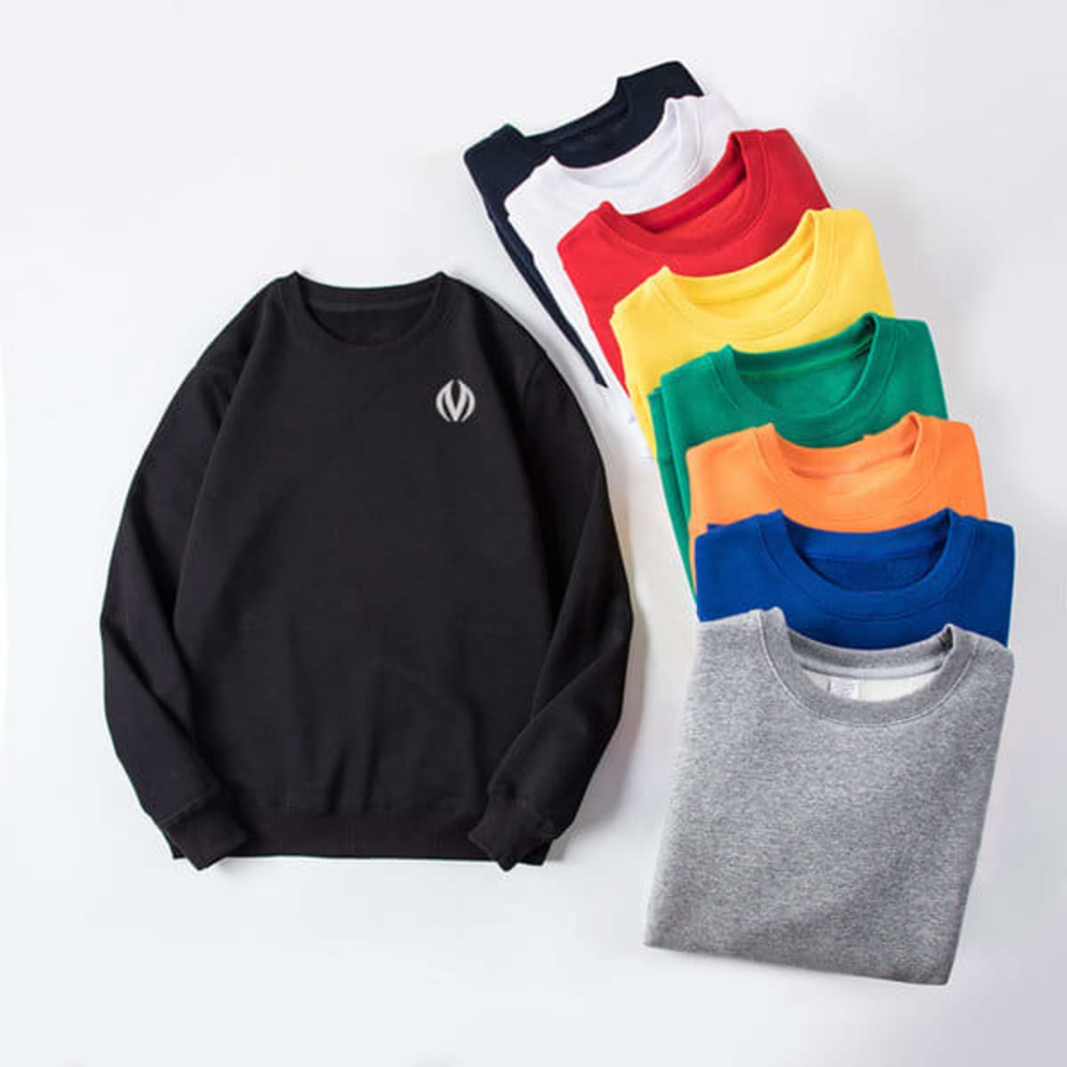 A black crewneck sweatshirt alongside eight other sweatshirts in various colours: white, red, yellow, green, blue, and grey, all stacked.