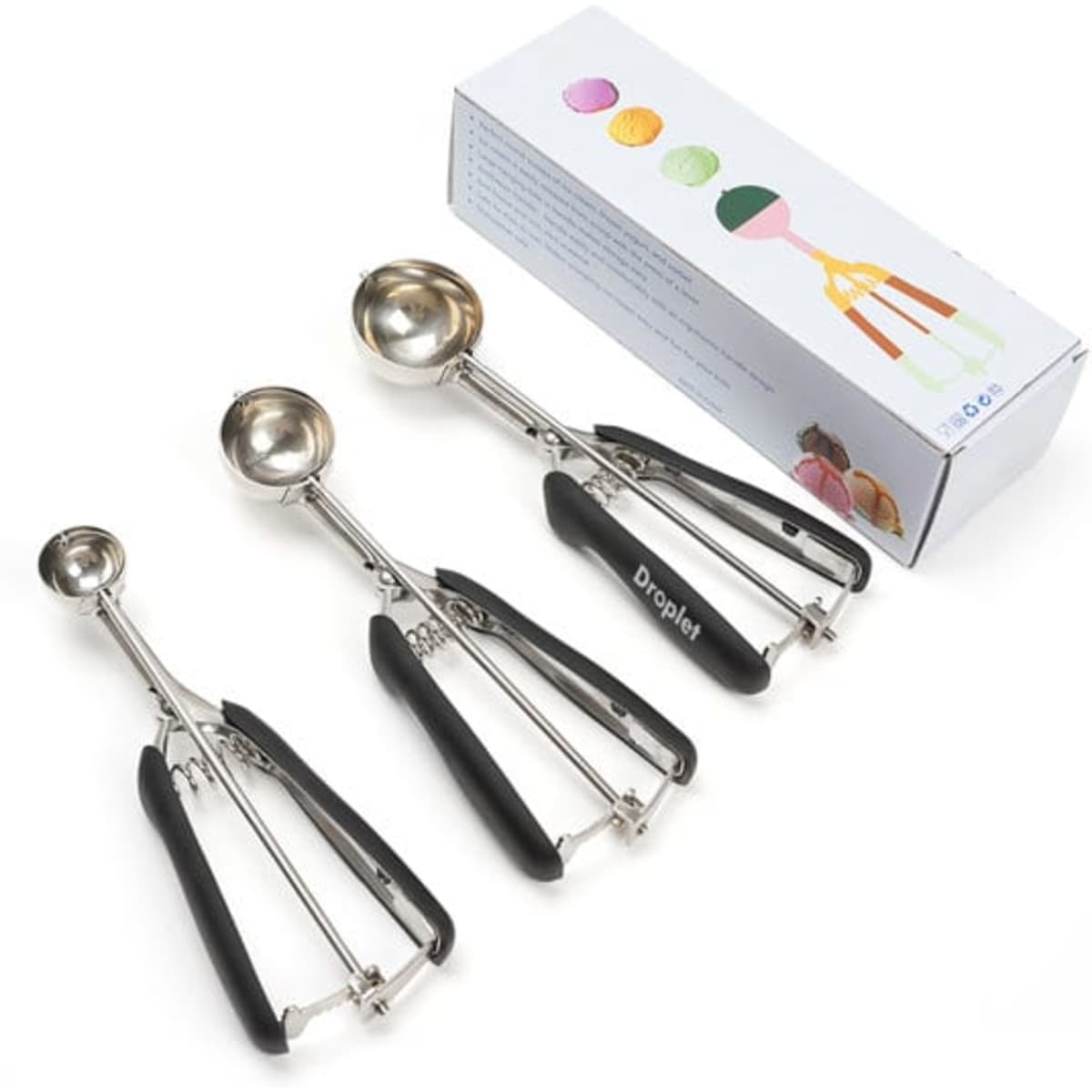 Three stainless steel ice cream scoops with black handles, displayed alongside their packaging.