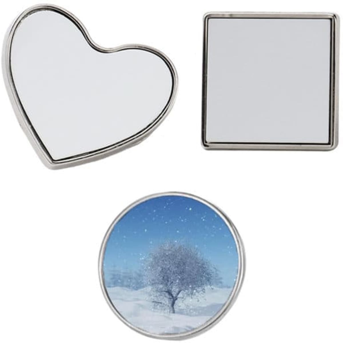 Three metal printing pin badges in heart, square, and round shapes, featuring a snowy tree design on one. Silver in colour.