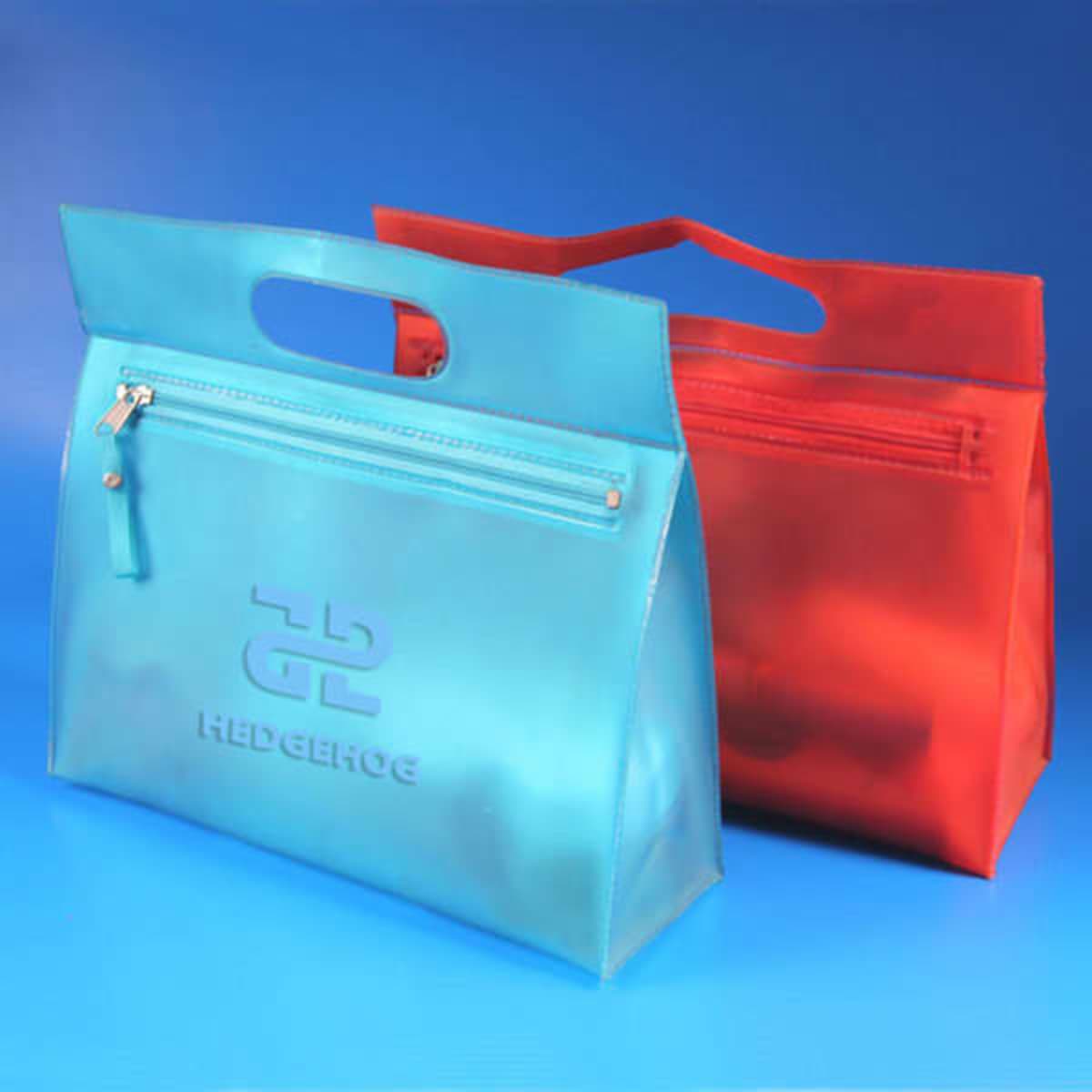 Frosted PVC cosmetic pouches in blue and red, featuring a handle and a zippered compartment, with a logo.