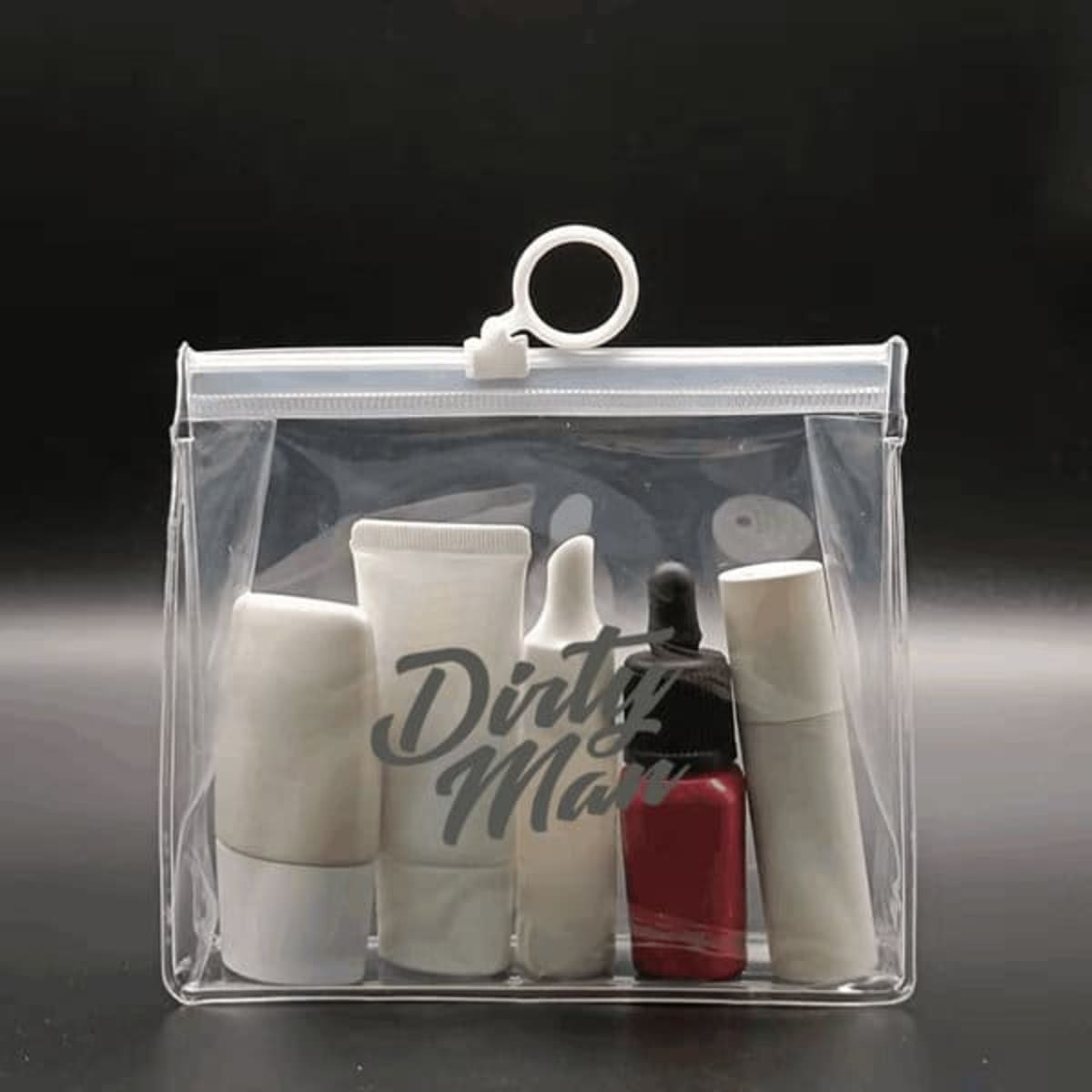A transparent cosmetic zipper bag containing various skincare and makeup products in white and red containers.
