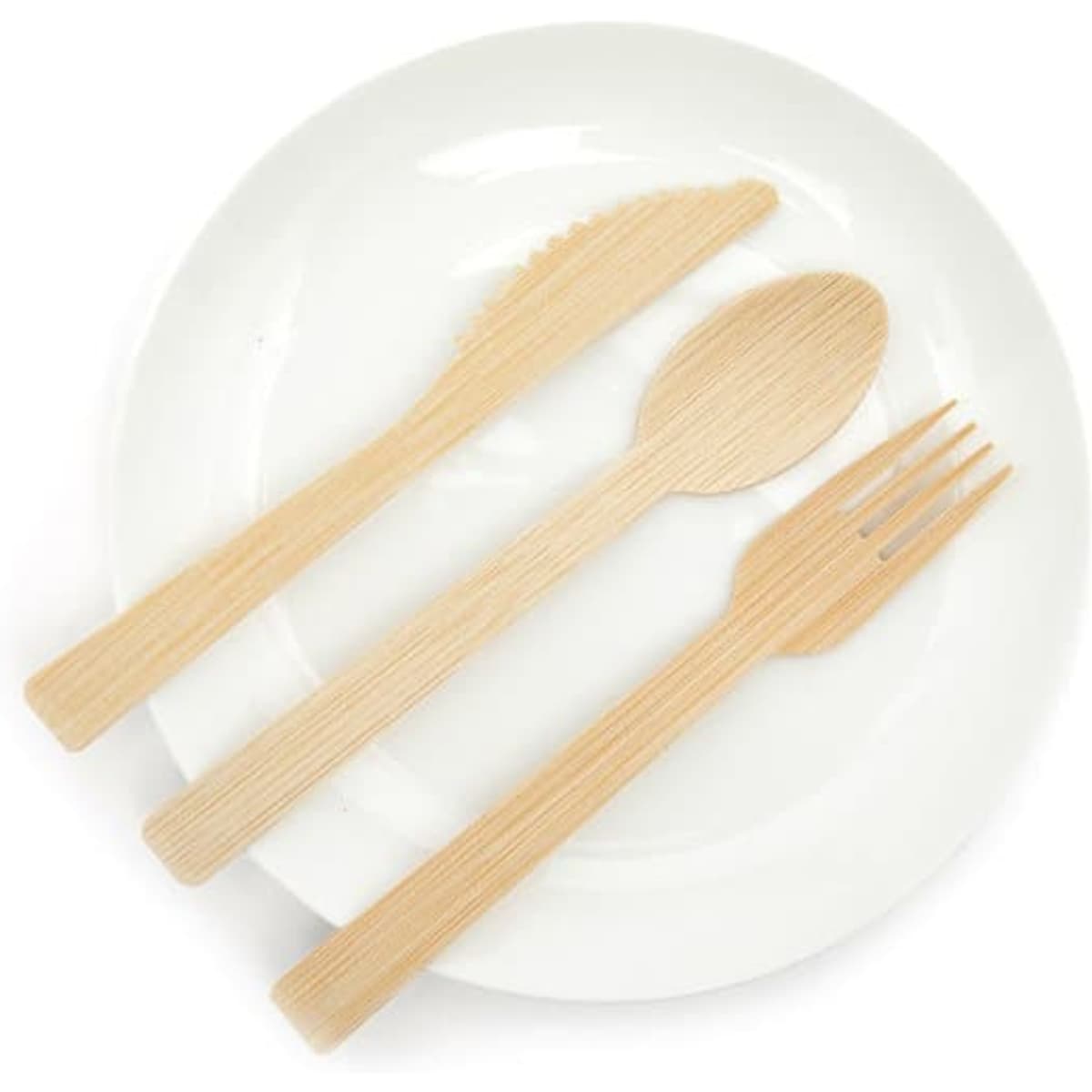 A biodegradable bamboo utensil set featuring a knife, fork, and spoon, placed on a white plate.