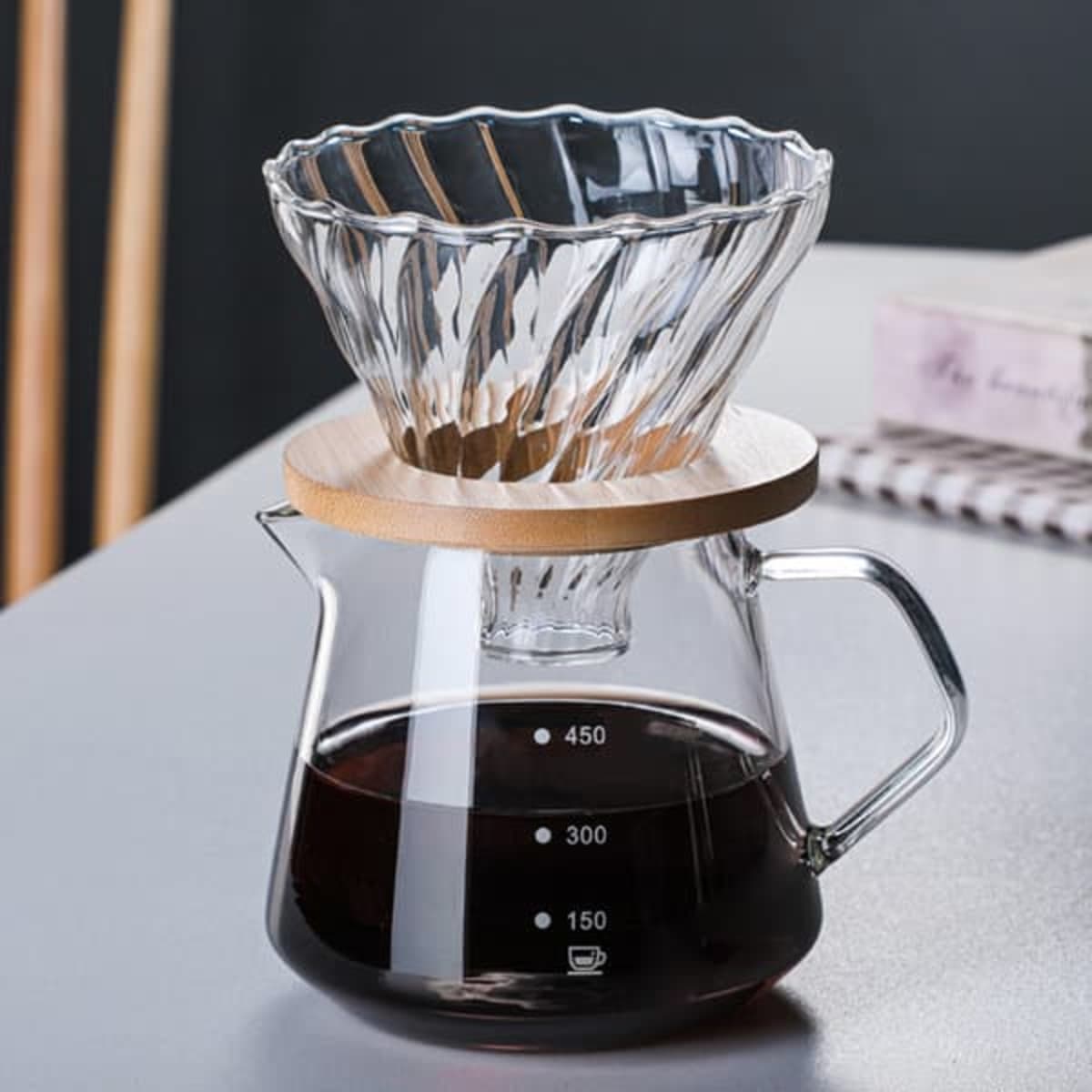 A coffee filter pot with a glass body, a wooden base, and a ribbed glass filter on top.