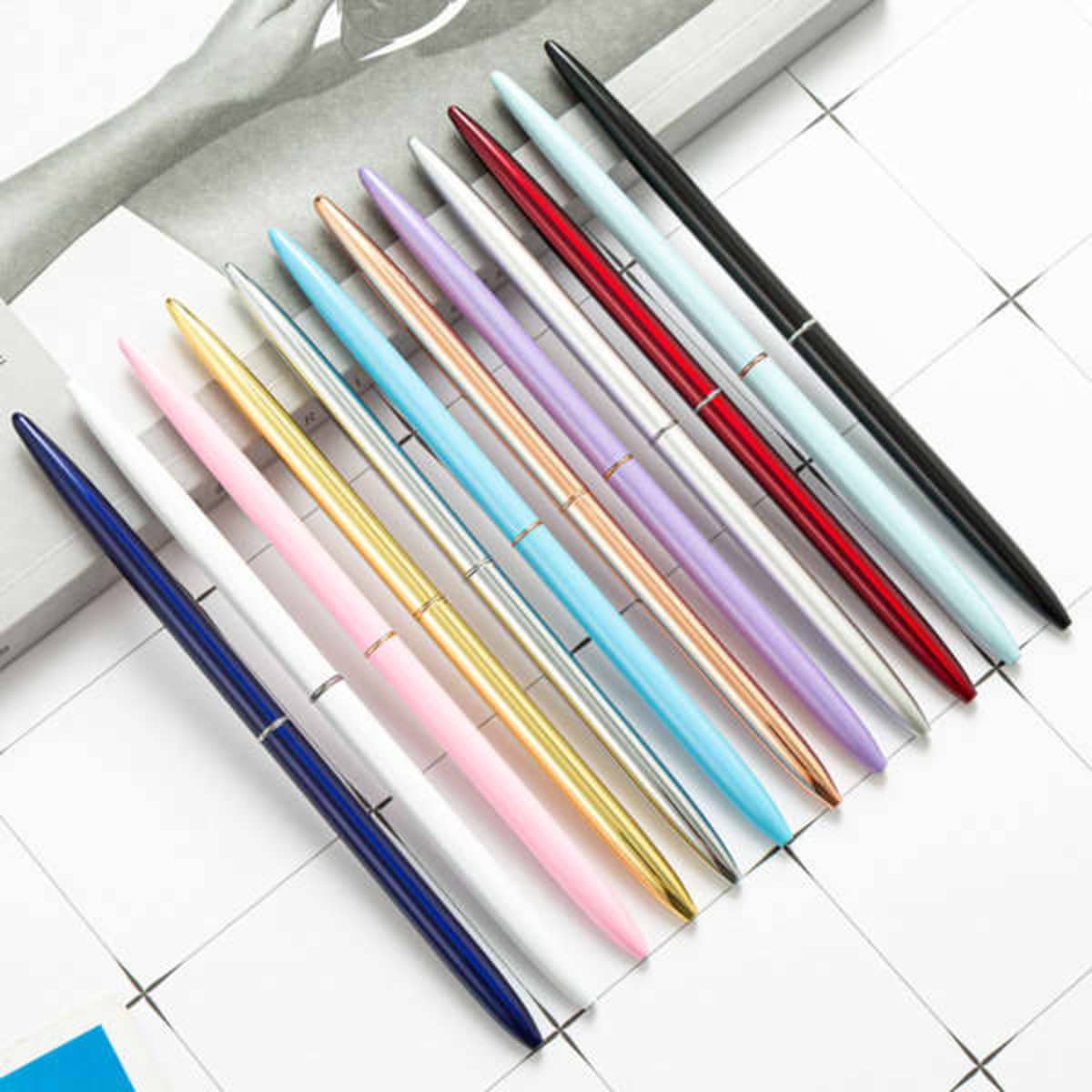 A collection of customizable ballpoint pens in various colours, including gold, silver, pink, blue, and black, with a logo.