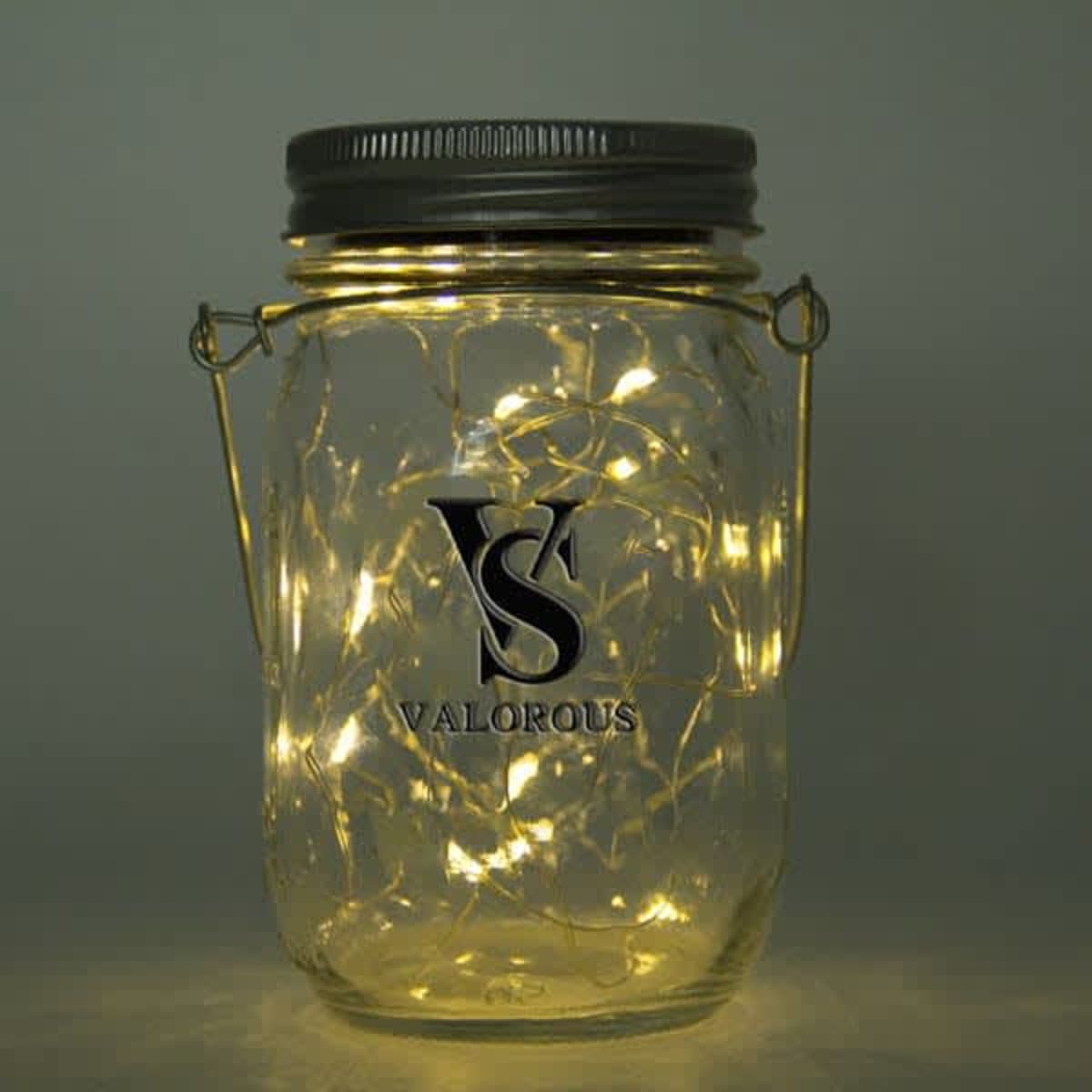 A glass mason jar with a metal lid contains warm white LED fairy lights, featuring a logo on the front.