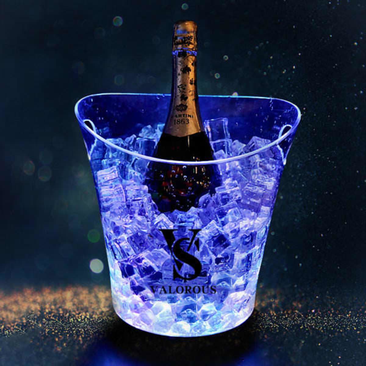 A transparent LED lighted ice bucket filled with ice and a bottle of champagne, featuring a logo.
