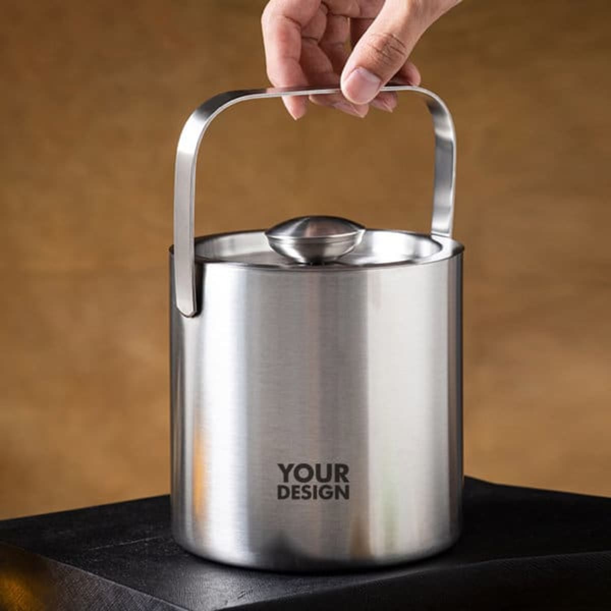 A stainless steel ice bucket with a handle and lid, featuring a logo. The bucket has a sleek, polished finish.