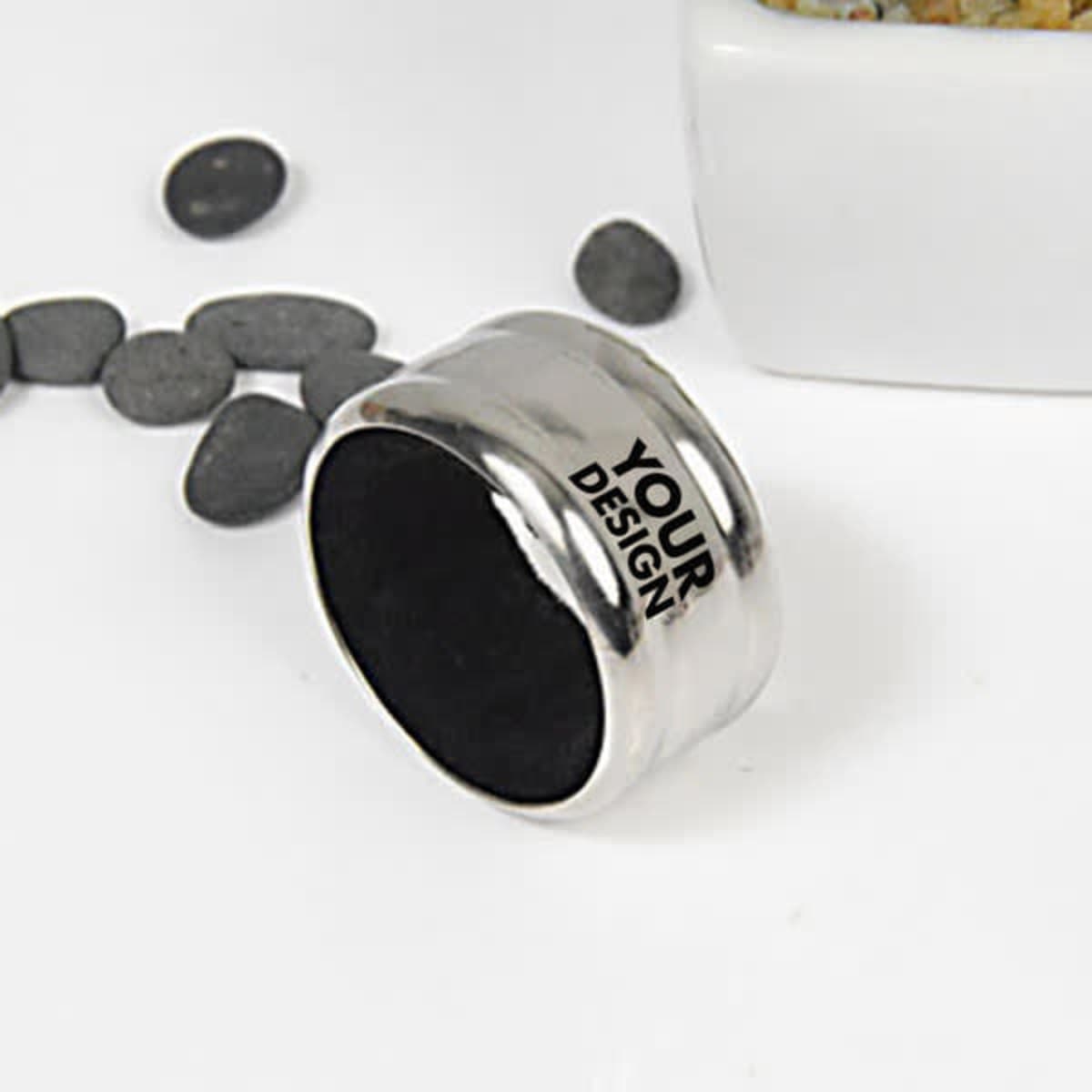 A stainless steel wine drip ring with a smooth finish, featuring a black interior and a design area, surrounded by pebbles.