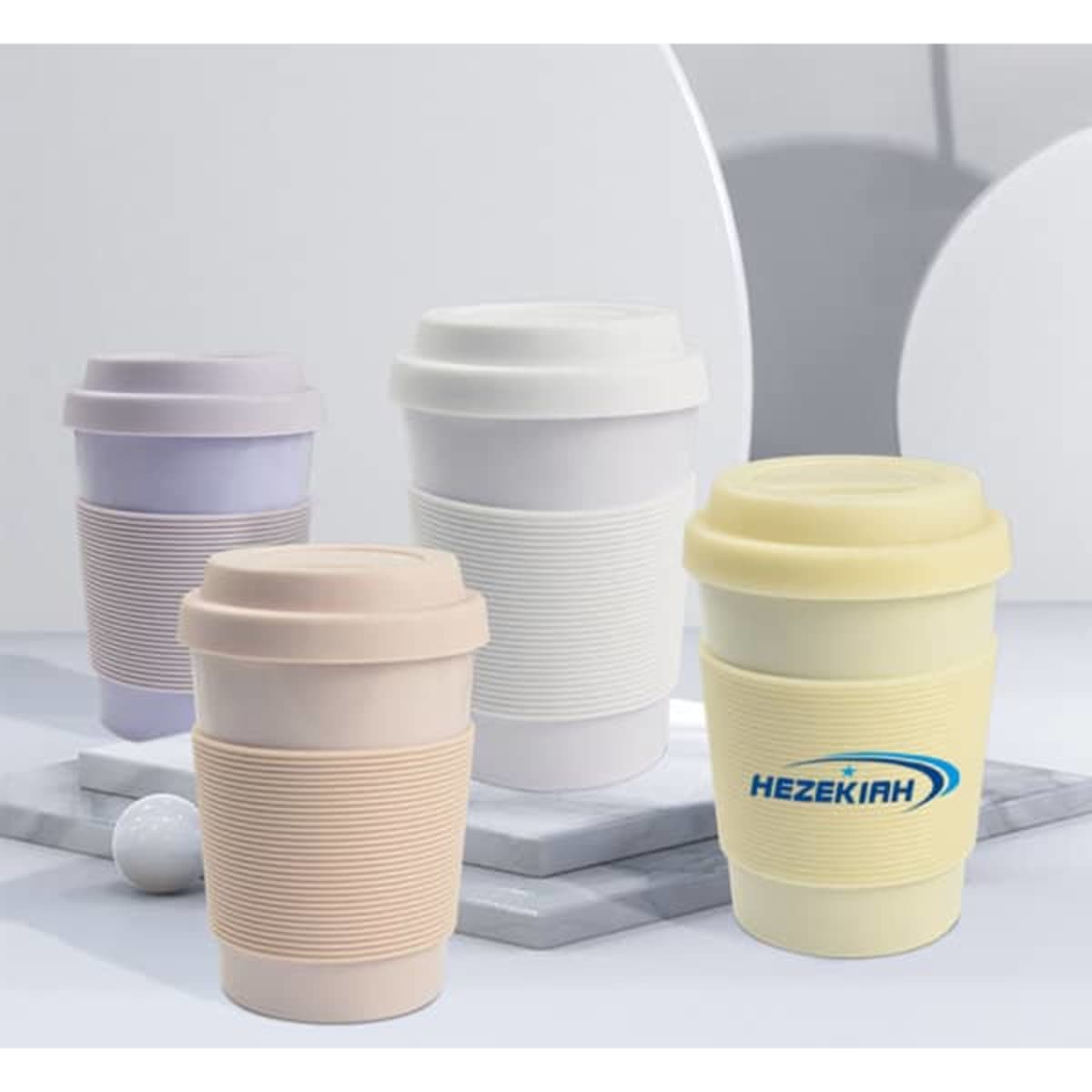 A set of four eco-friendly coffee mugs in pastel colours, each with silicone lids and textured grips. One mug features a logo.