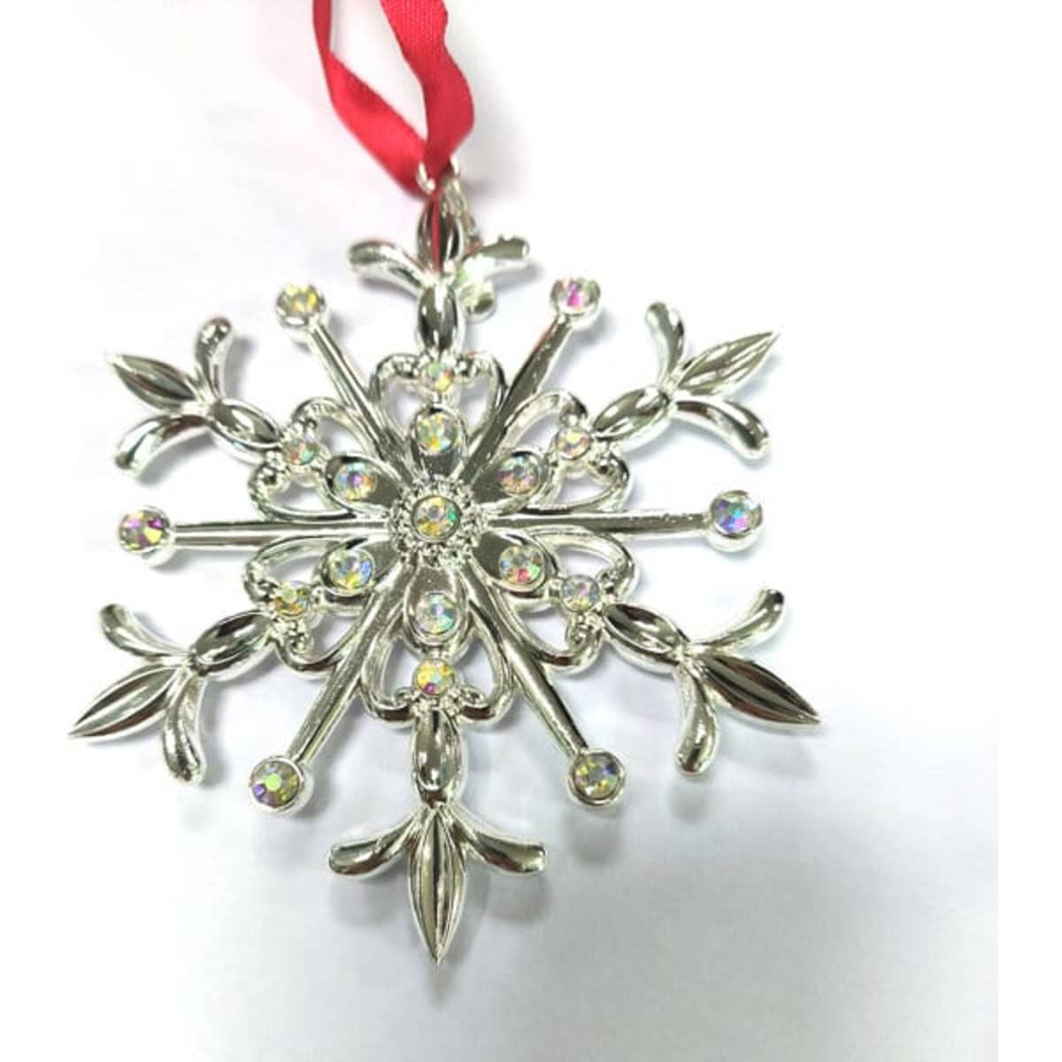 A metallic snowflake charm with a silver finish and sparkling rhinestones, featuring a red ribbon for hanging.