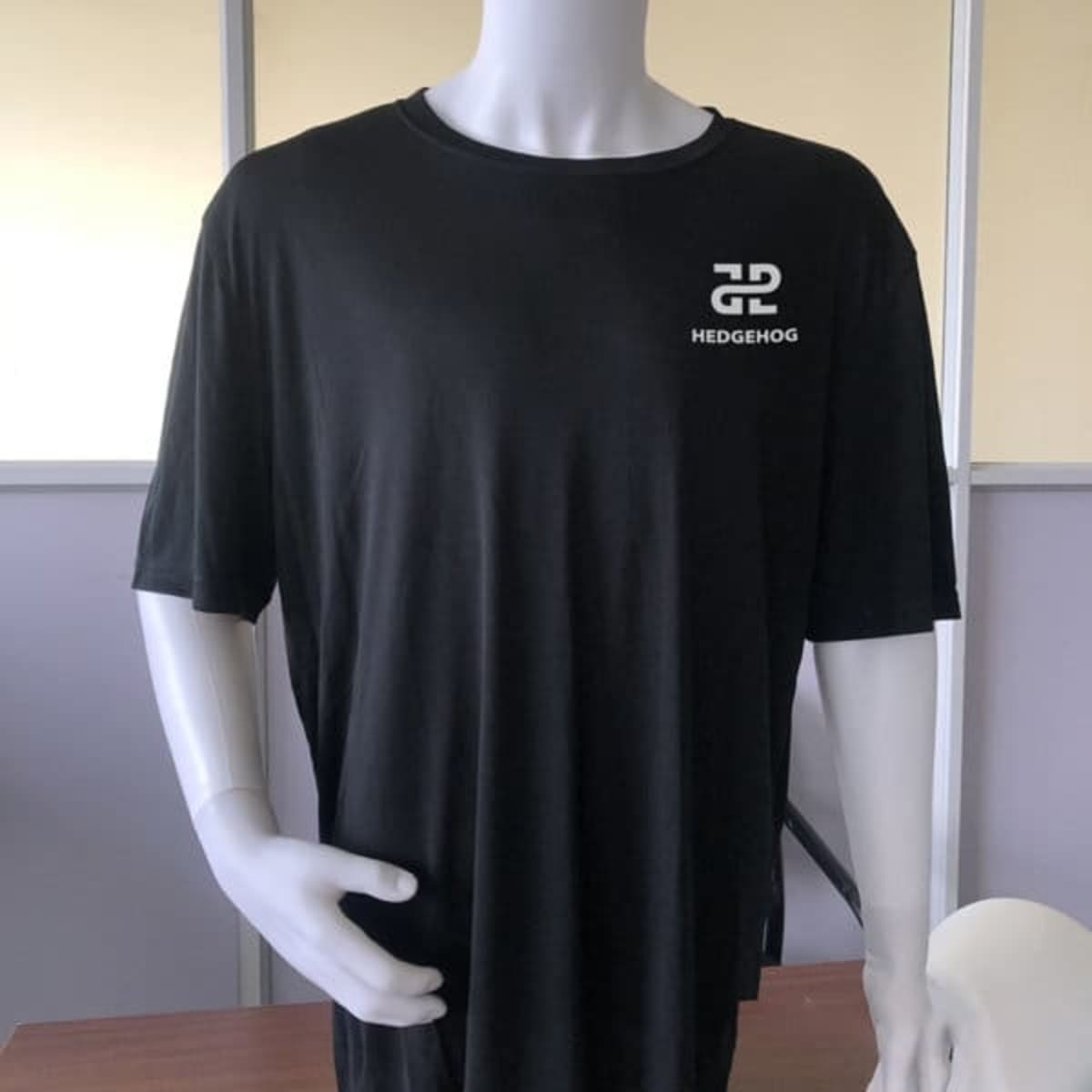 A black recycled polyester T-shirt on a mannequin, featuring a small logo on the front.