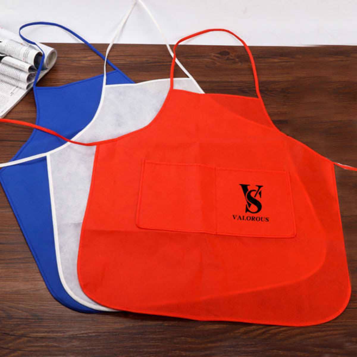 A set of three RPET disposable aprons in blue, red, and white, featuring a logo on one apron.
