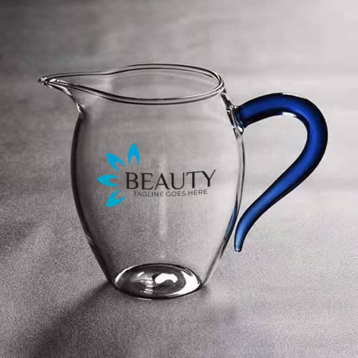 A drink jug made of clear borosilicate glass with a blue handle and featuring a logo.