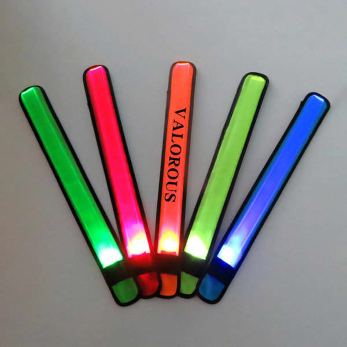 A collection of five LED slap bracelets in green, red, orange, and blue, featuring one with a logo.