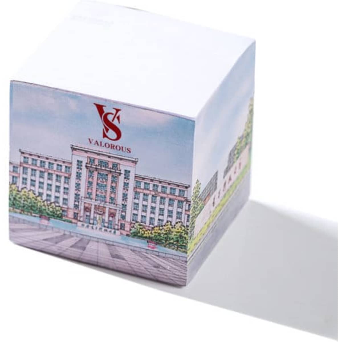 A white sticky note cube featuring an illustrated building on one side and a logo on top.