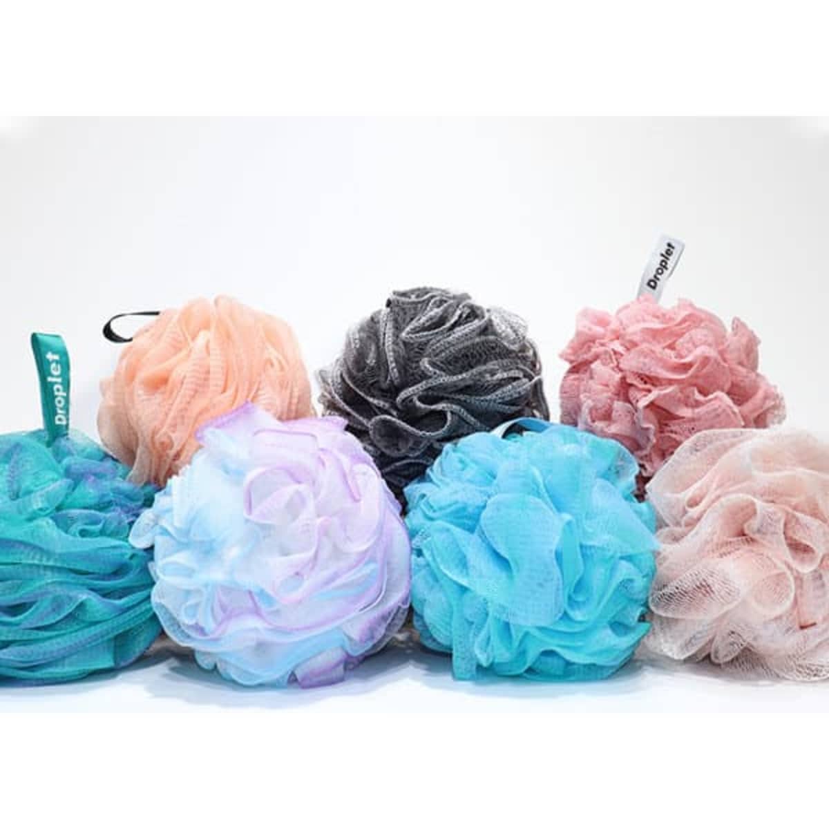 Collection of flower-shaped shower balls in various pastel colours, including blue, pink, and black, with tags.