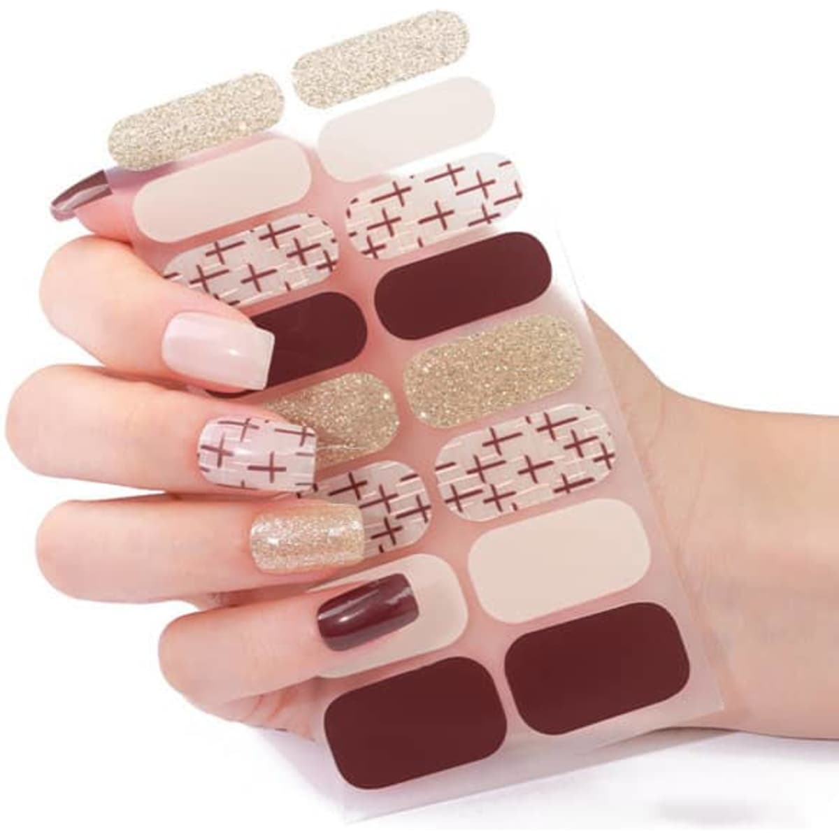 A hand holding a sheet of custom nail art stickers in shades of nude, burgundy, and glittery gold.