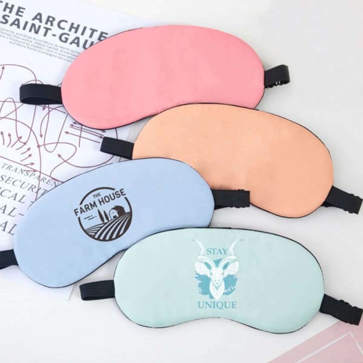 A set of sleep masks in pink, peach, blue, and green, featuring various designs and an adjustable strap.