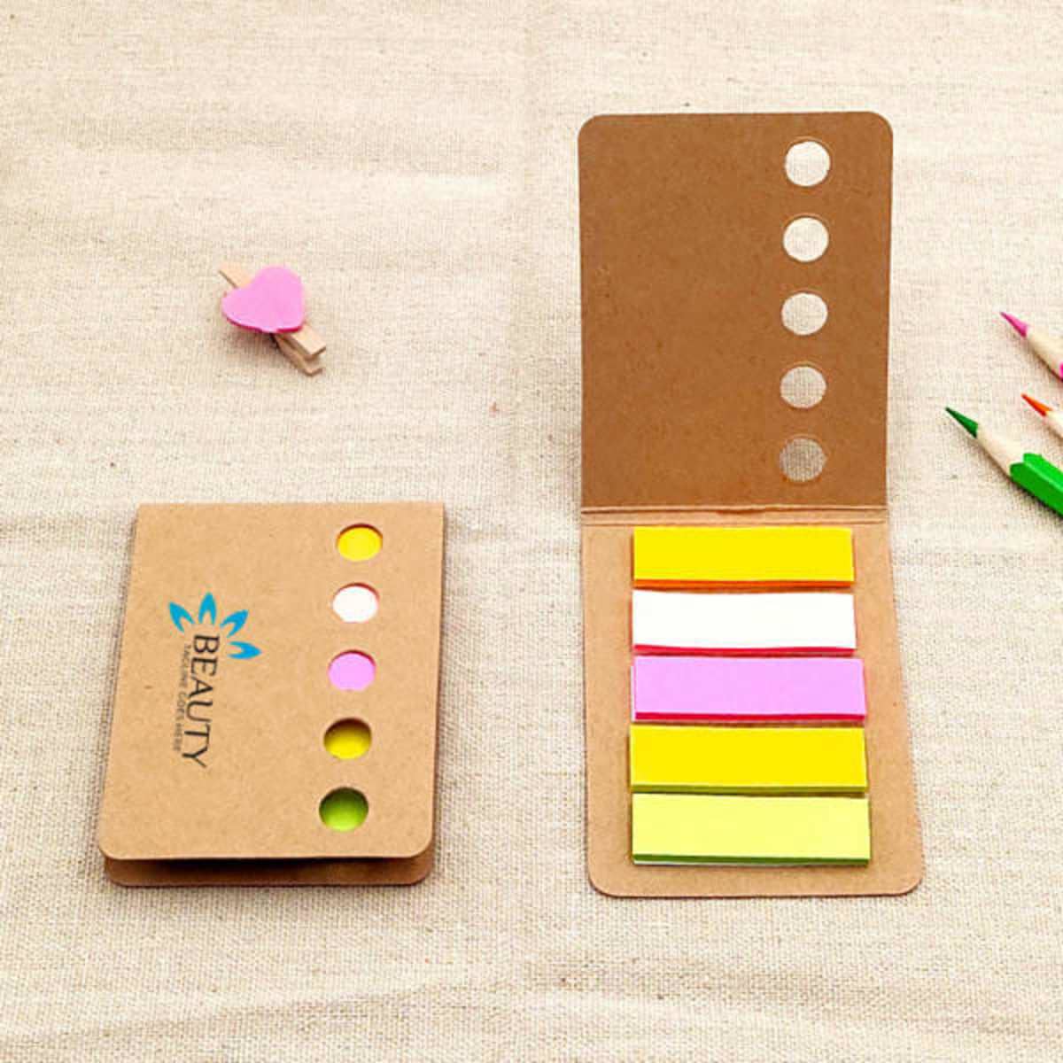 Bright colour sticky index tabs in a cardboard holder, featuring pink, yellow, white, and green tabs. Includes a logo.