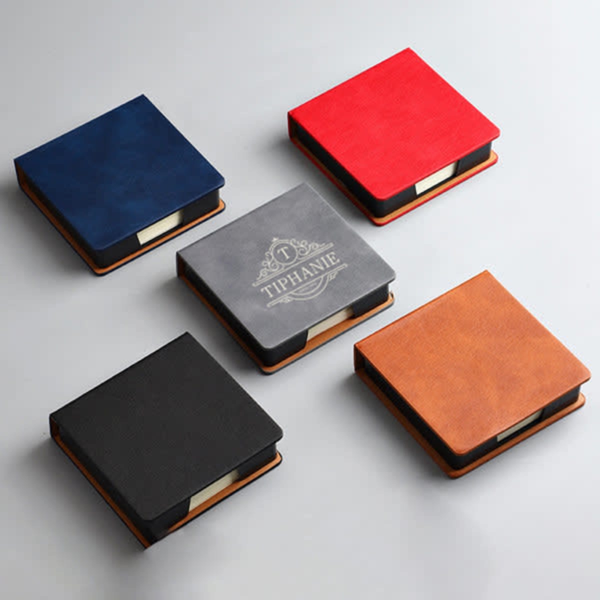 A PU leather note storage box in navy, grey, red, black, and brown, featuring paper inside and a logo on one box.