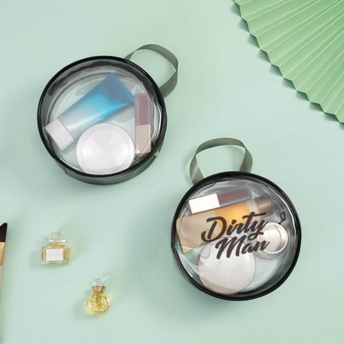 Two clear PVC round cosmetic bags in black, containing various toiletry items, with small handles for easy carrying.