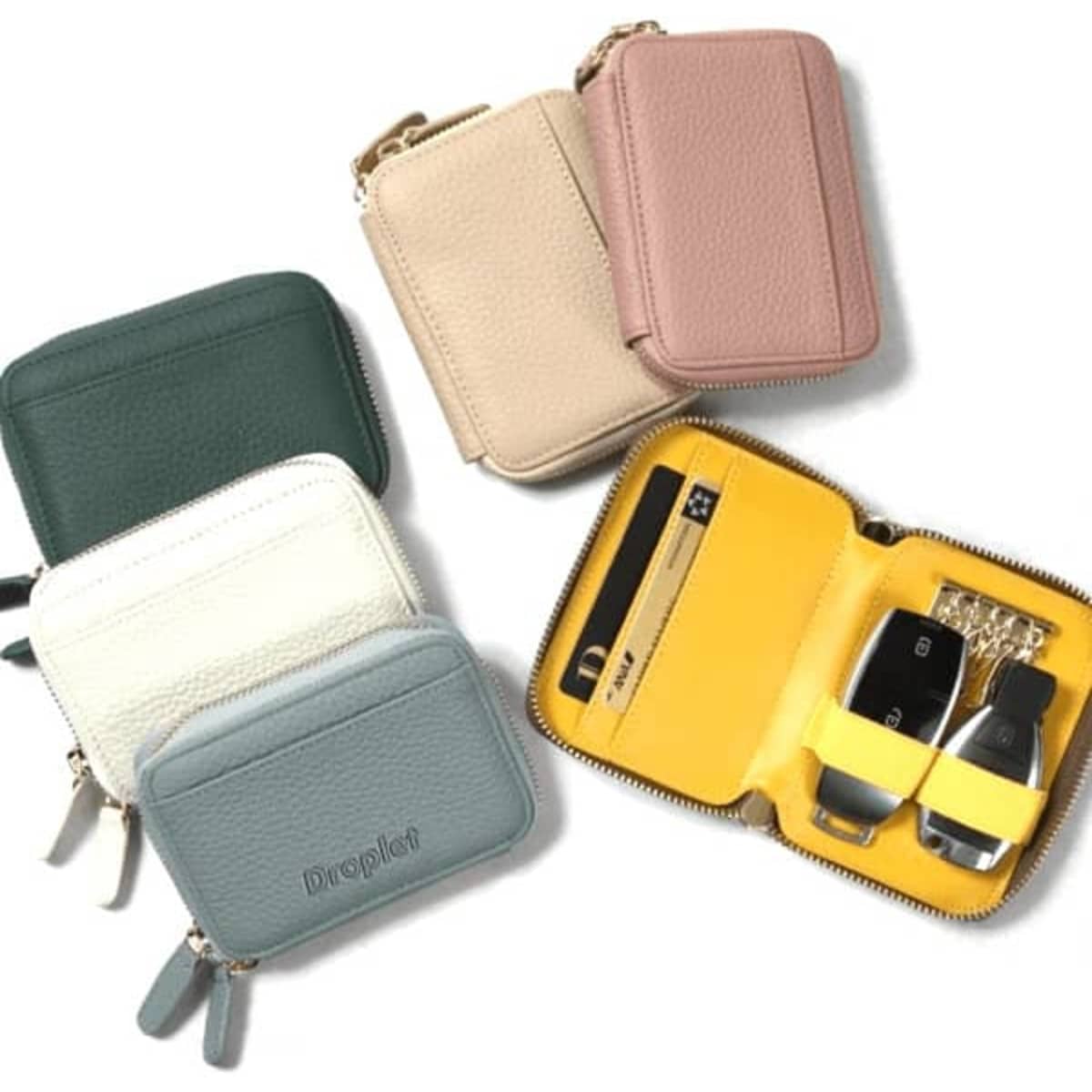 A range of Portable PU Key Holder Wallets in green, cream, beige, pink, and light blue, featuring a zippered design and interior compartments.