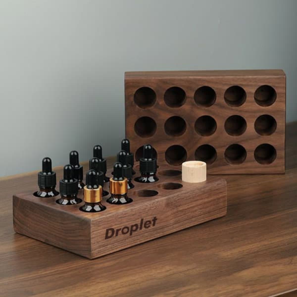 A wooden essential oil tray featuring multiple holes to hold bottles, in a rich walnut finish.