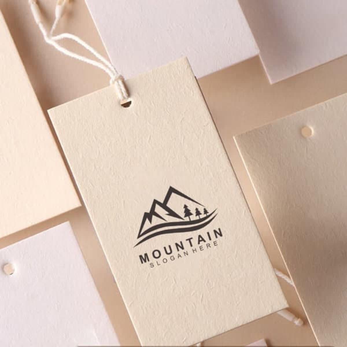 A custom cotton clothing hang tag in cream with a mountain logo. Features a string for attachment.