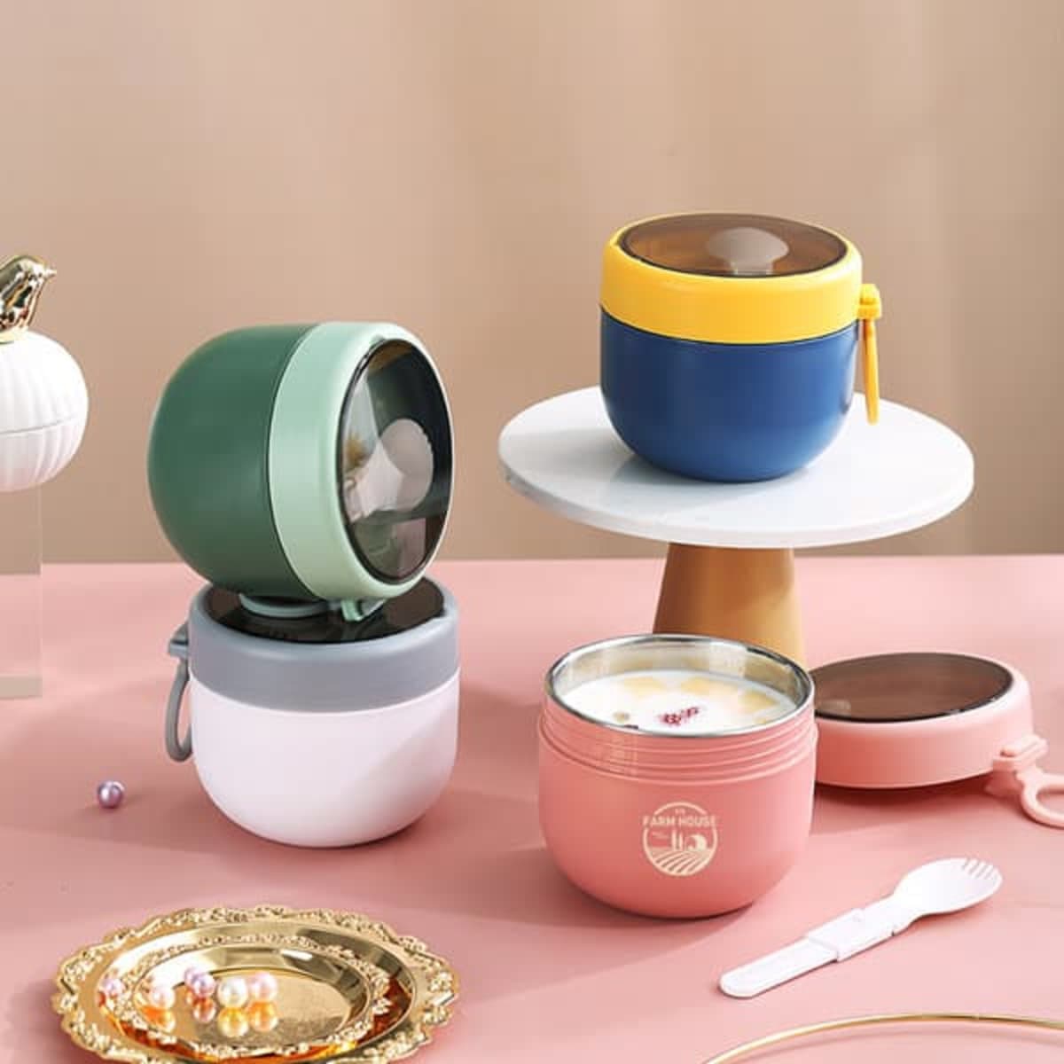A set of four stainless steel insulated breakfast cups in green, blue, pink, and white, featuring various lids and a logo.