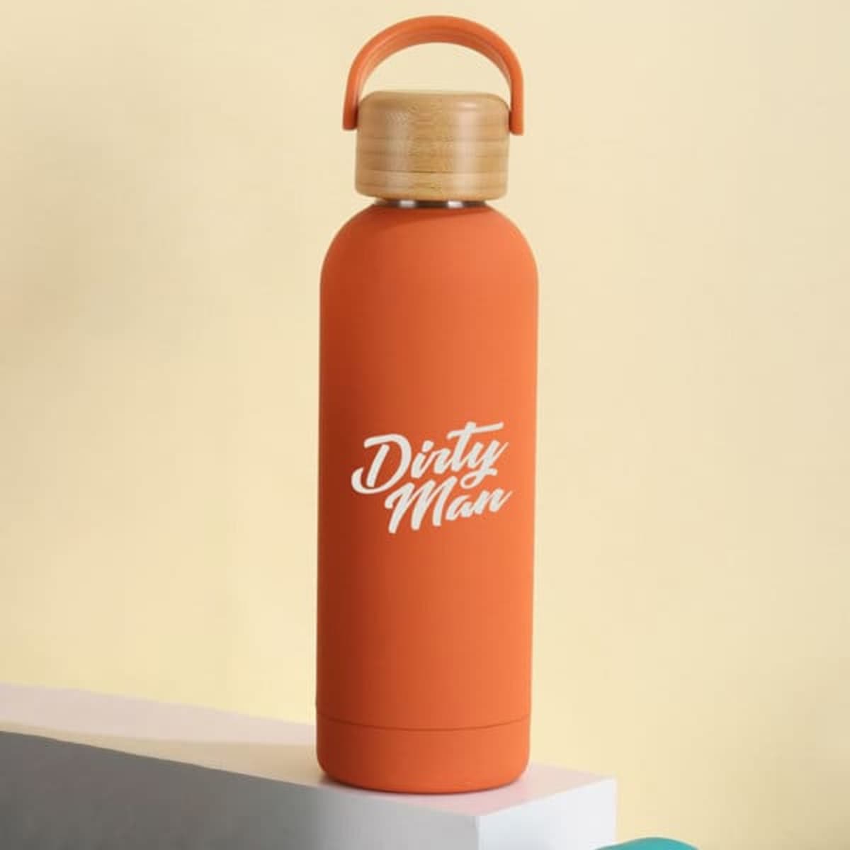 An orange insulated drink bottle with a bamboo lid and a handle, featuring a logo.