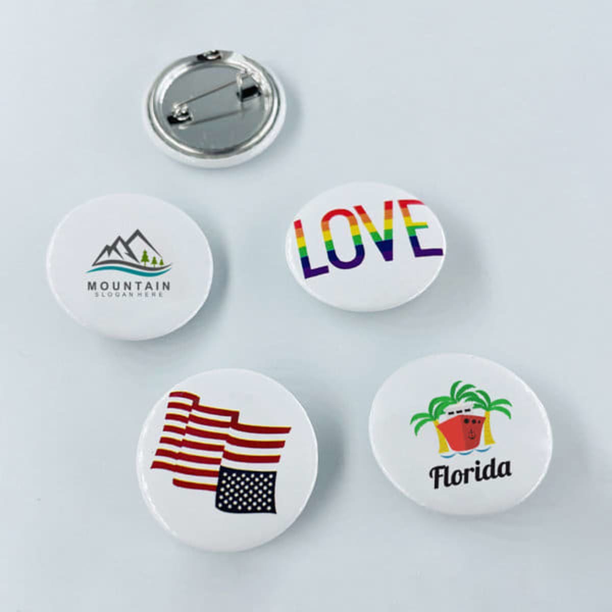 A selection of round pin button badges featuring various designs, including mountains, rainbow text, flags, and palm trees.