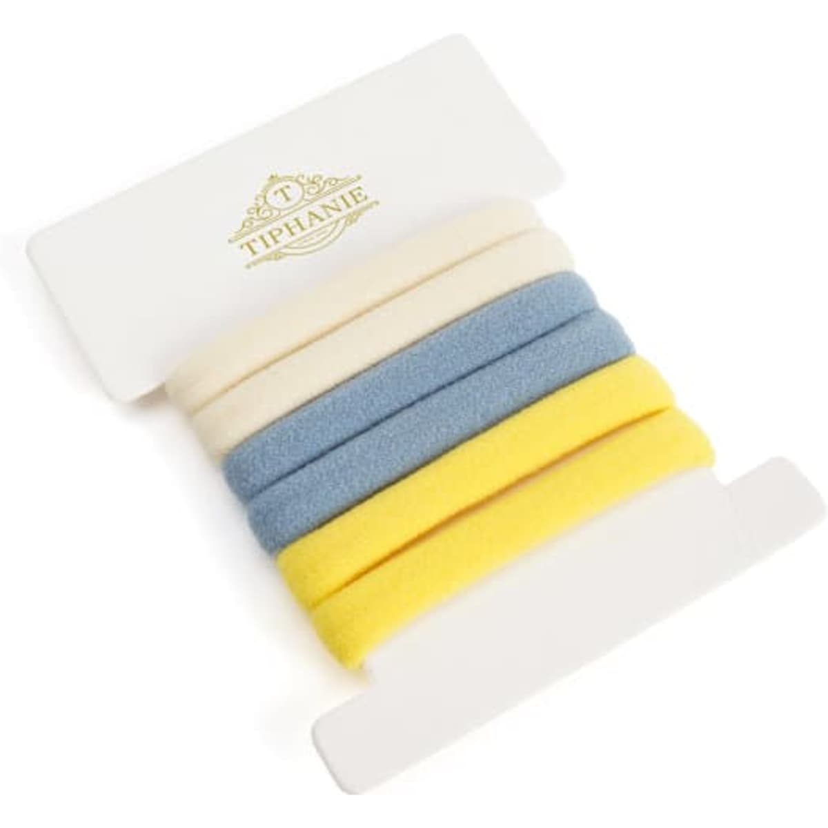 A set of hair ties in blue, yellow, cream, and a textured finish, presented on a white backing with a logo.