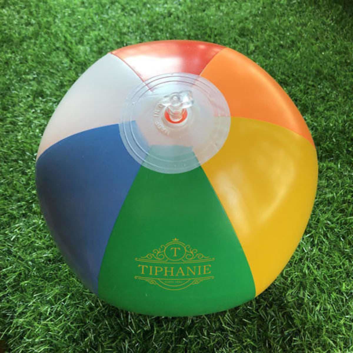 A PVC inflatable beach ball featuring six vibrant colours: red, orange, yellow, green, blue, and purple. It has a logo.