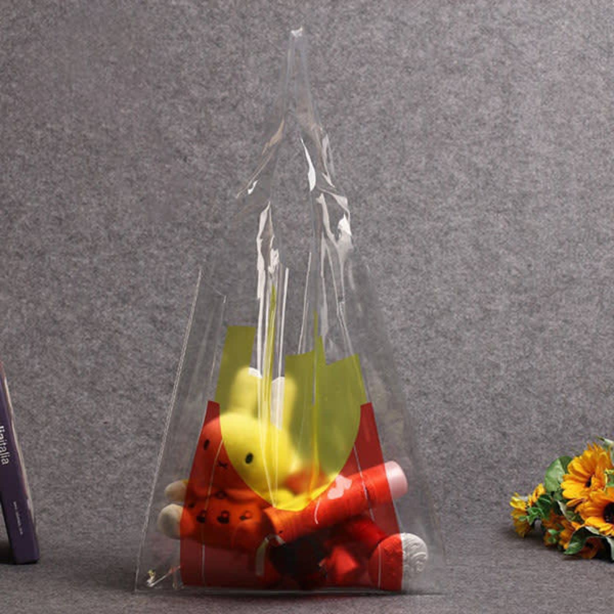 A clear PVC tote bag containing colourful plush toys, featuring a logo on the exterior.