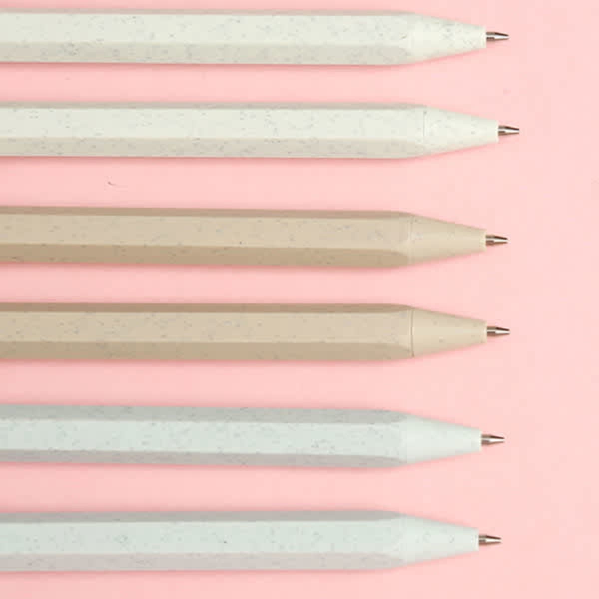 A collection of wheat straw mechanical pencils in light tones, displayed against a pink background.