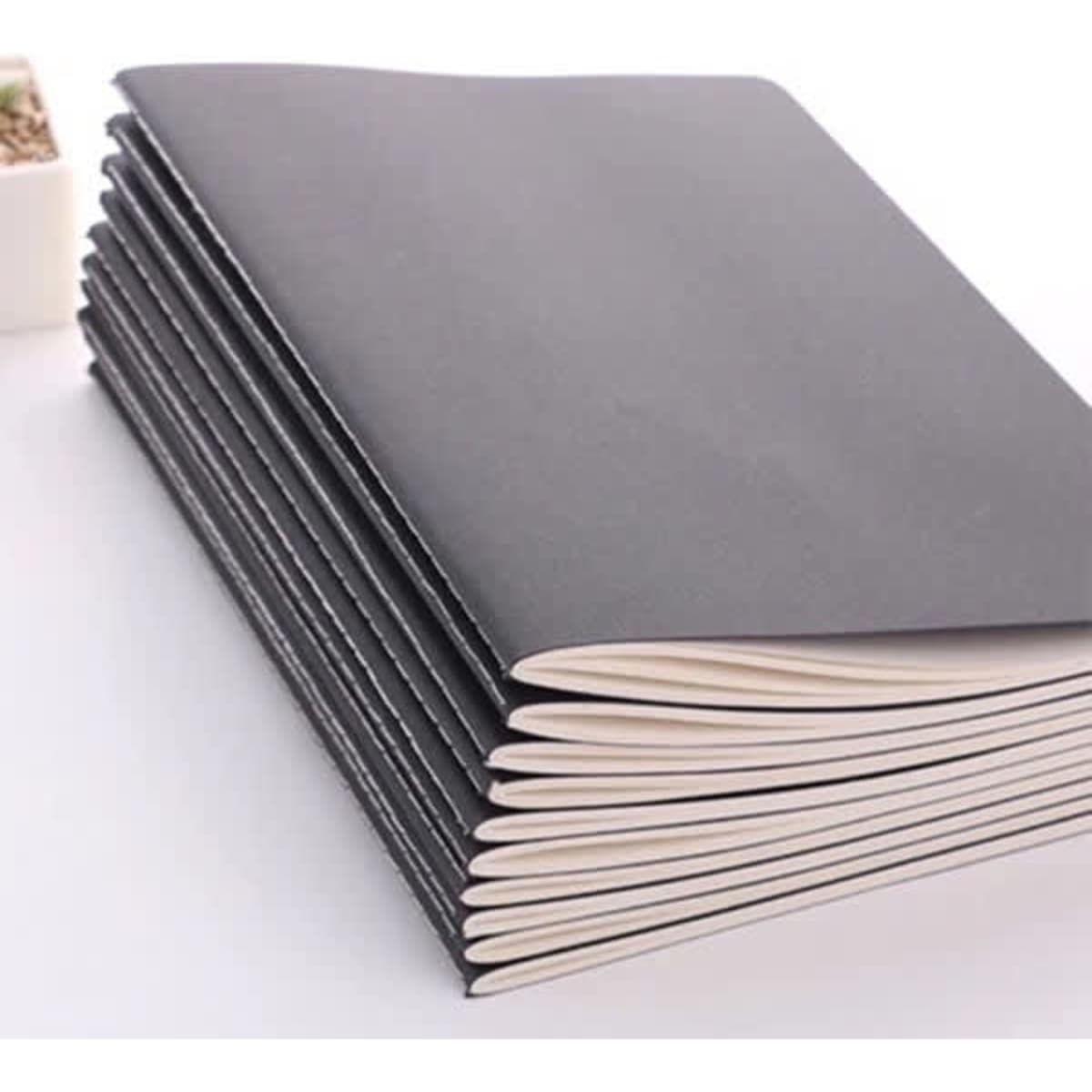 A stack of vintage kraft paper notebooks featuring a black cover and cream-coloured pages.