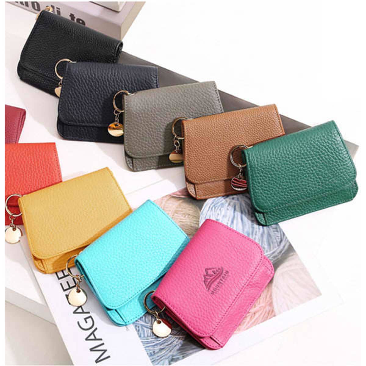 A row of small RFID blocking wallets in various colours, including black, green, brown, turquoise, pink, and yellow. Each wallet has a keyring.