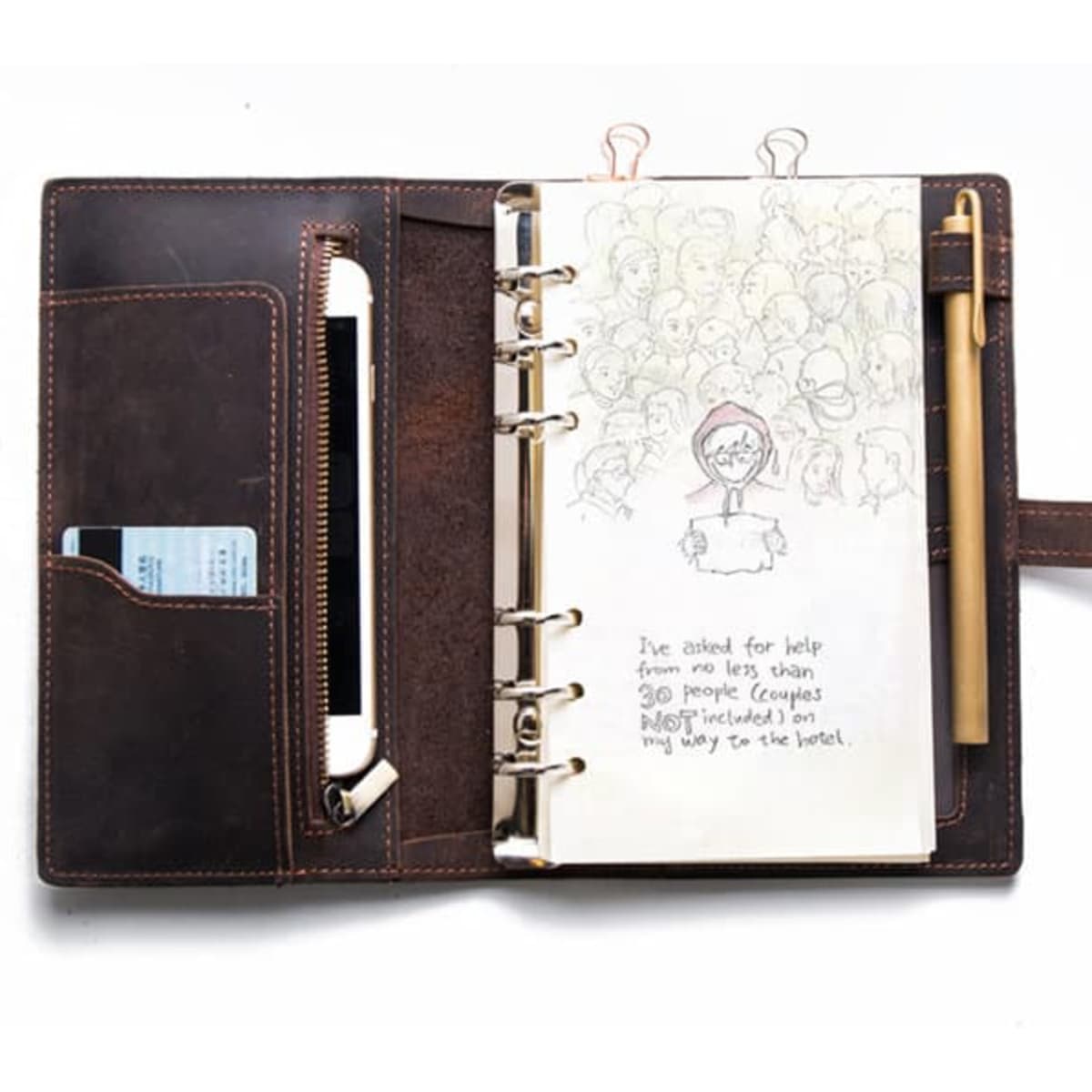 A brown multifunctional vintage spiral travel notebook binder with a pen, pockets, and blank pages inside.